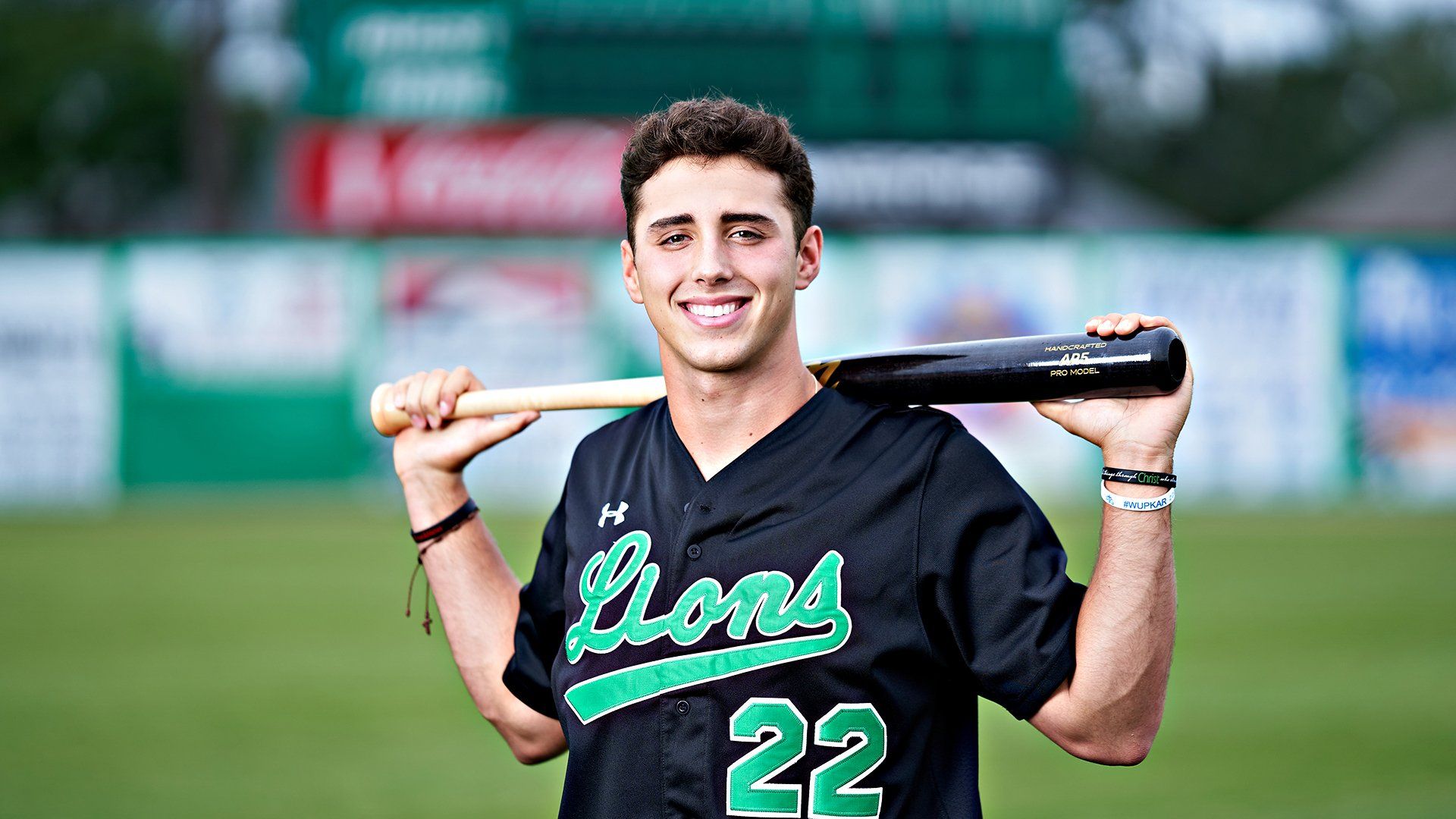 A young man is holding a baseball bat over his shoulder.