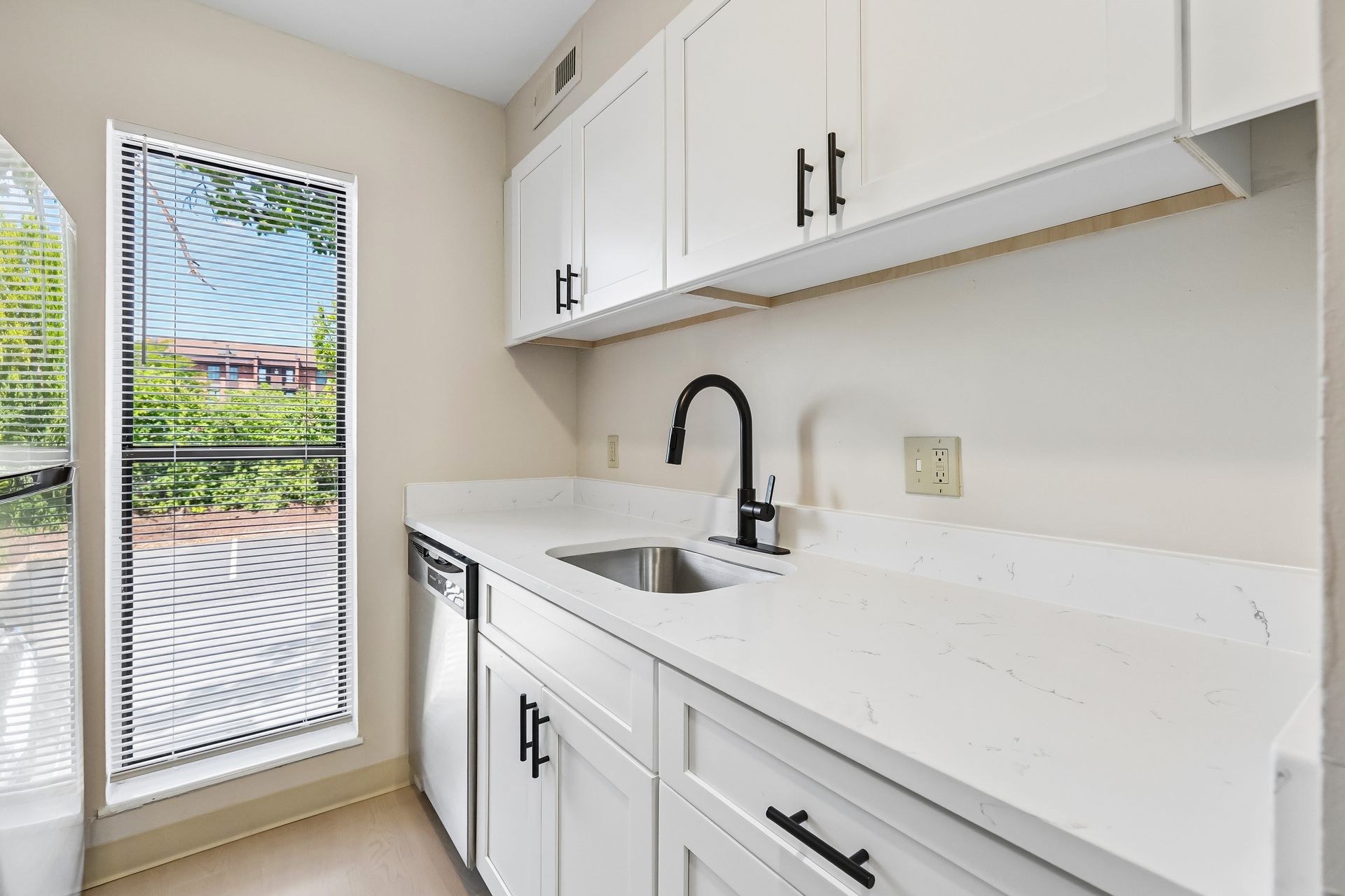 Kitchen with white cabinetry, a sink, and large window at Village Park Apartments