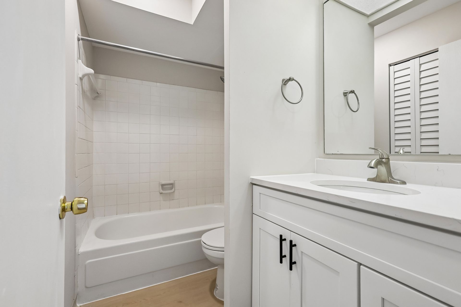 Bathroom with a white vanity and bathtub with shower at Village Park Apartments