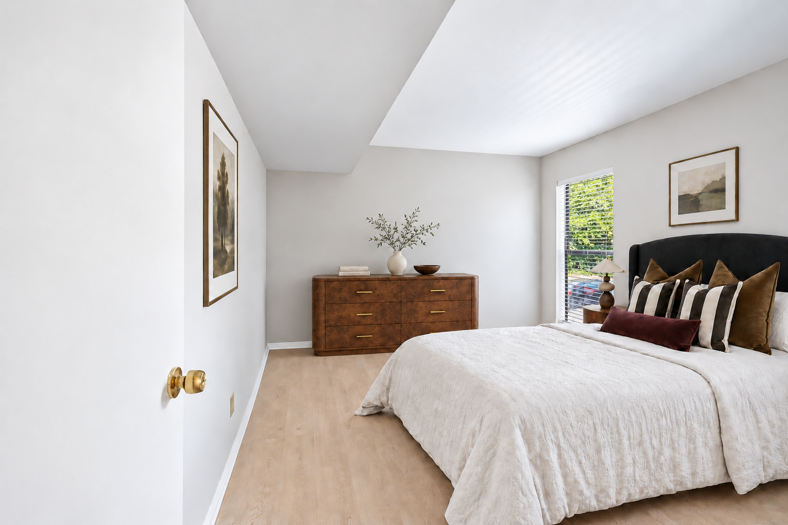 Staged bedroom with a bed, dresser, and window at Village Park Apartments