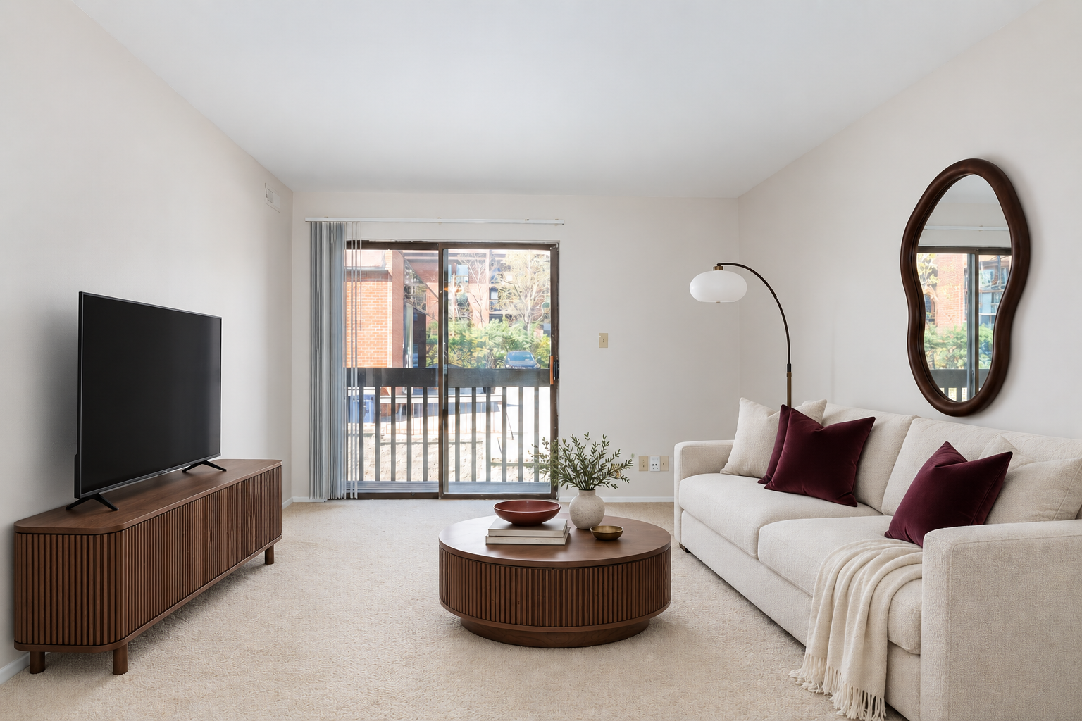 Staged living room with a sofa and television console at Village Park Apartments