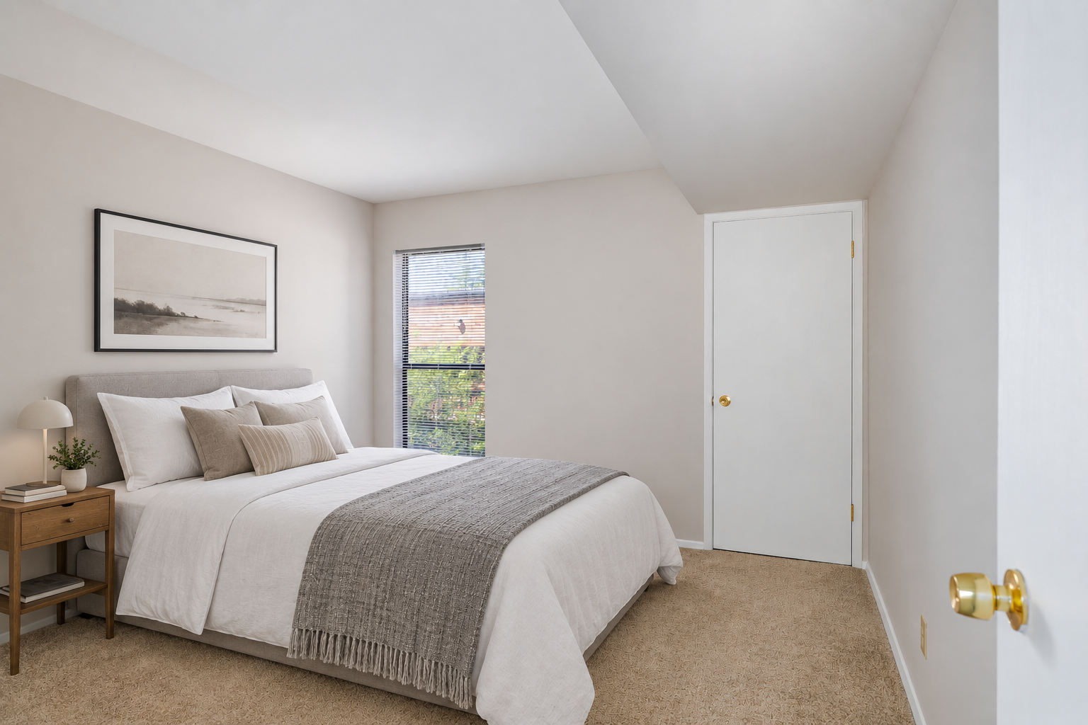Staged bedroom with a bed, nightstand, and window at Village Park Apartments