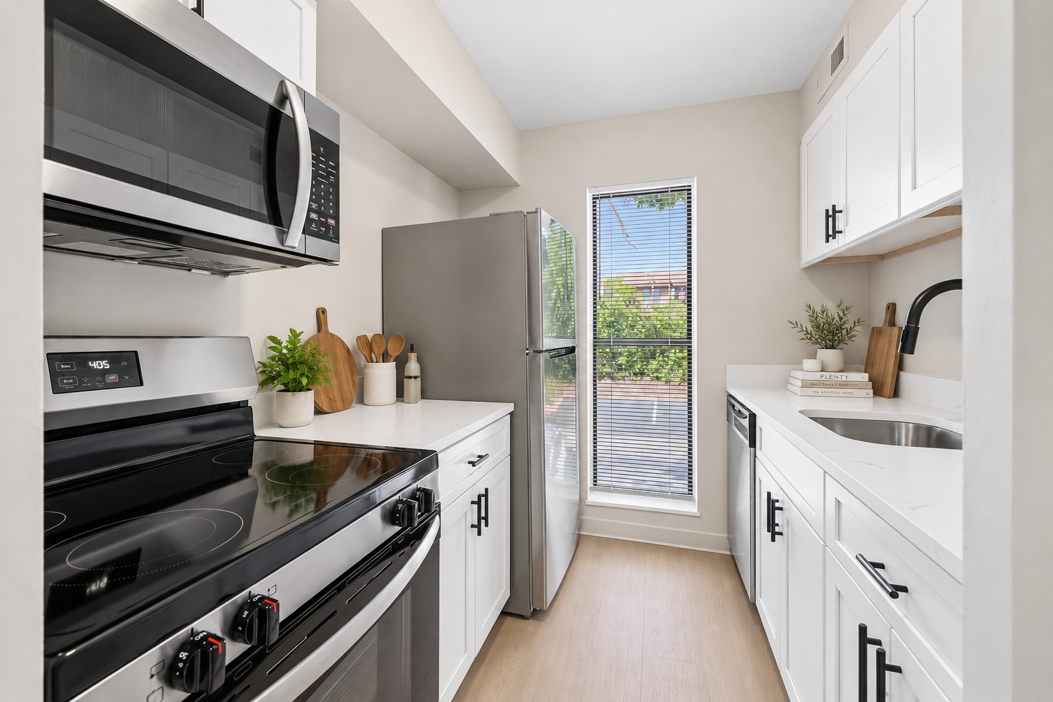 Apartment kitchen with white cabinets and stainless steel appliances at Village Park Apartments