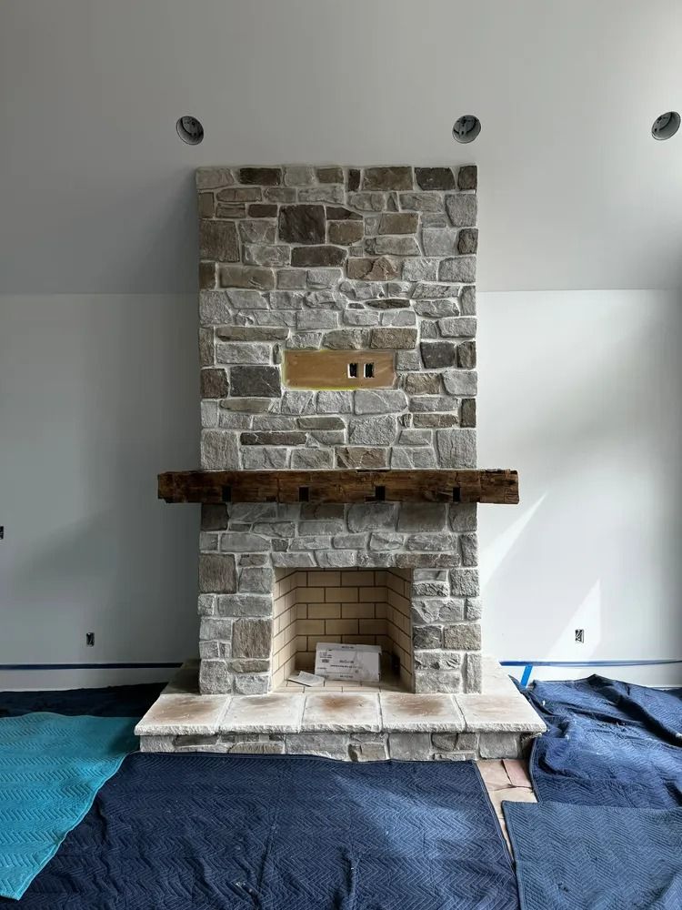 Stone fireplace under construction with blue floor coverings in a white room