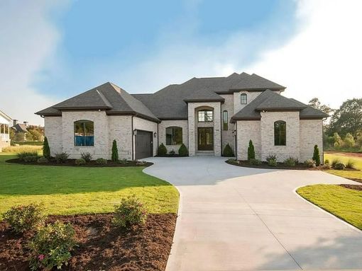 Modern gray stone suburban house with a front walkway, lawn, and landscaped entryway