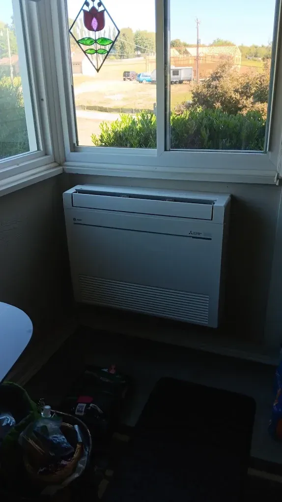 Small room with a window, wall-mounted heater, and a sticker on the glass overlooking a road.