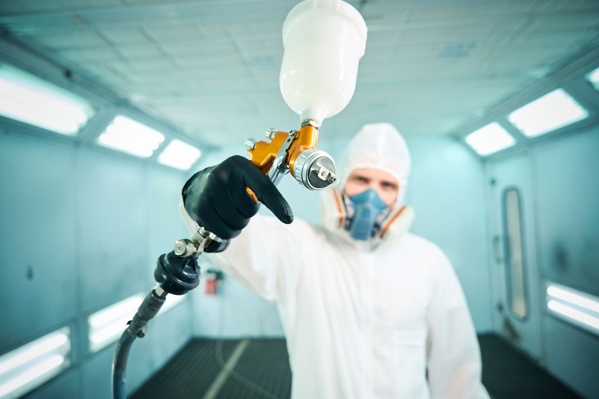 Painter holding a spray paint machine towards the camera.