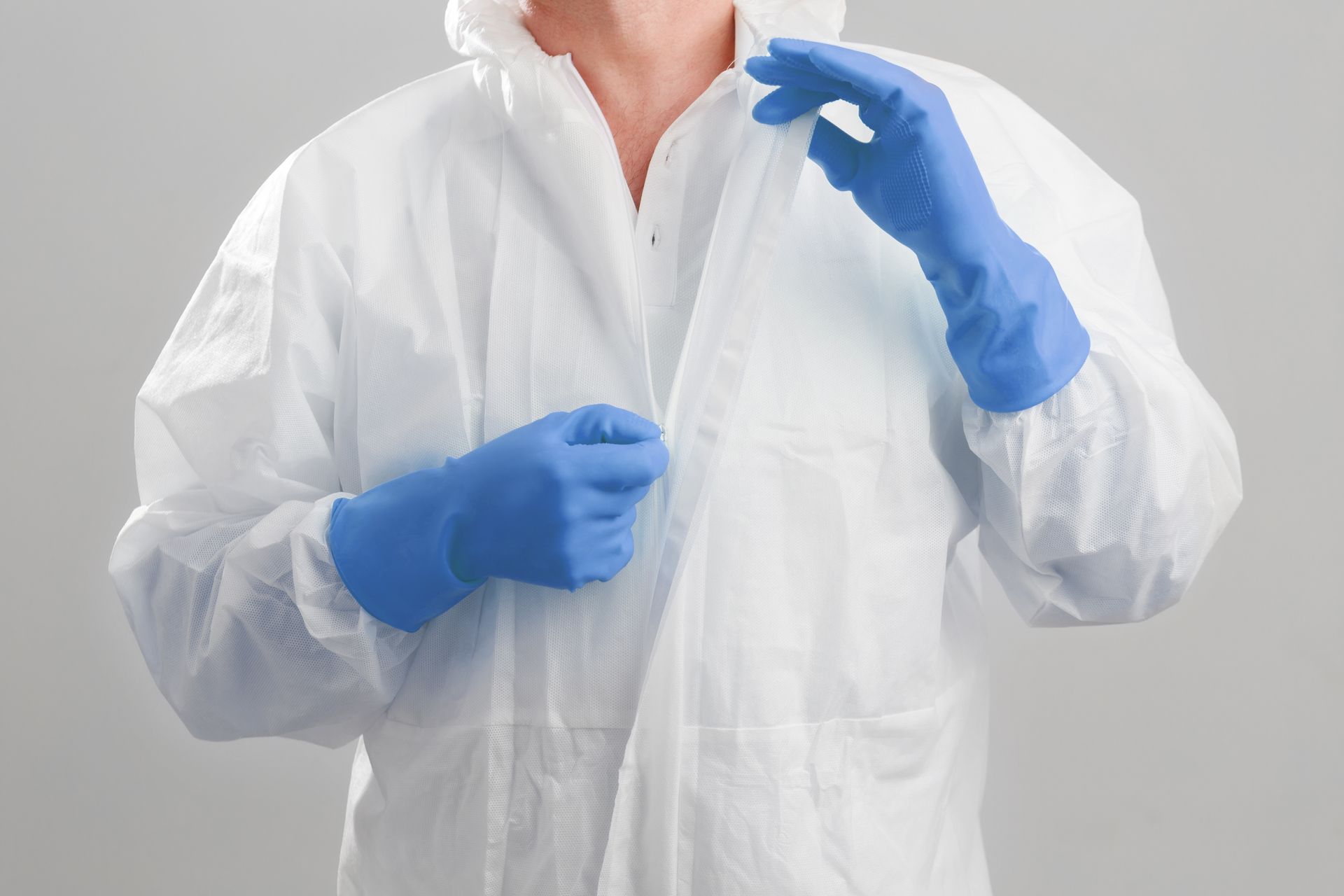 Man in a protective hazmat suit unzipping his PPE after finishing work