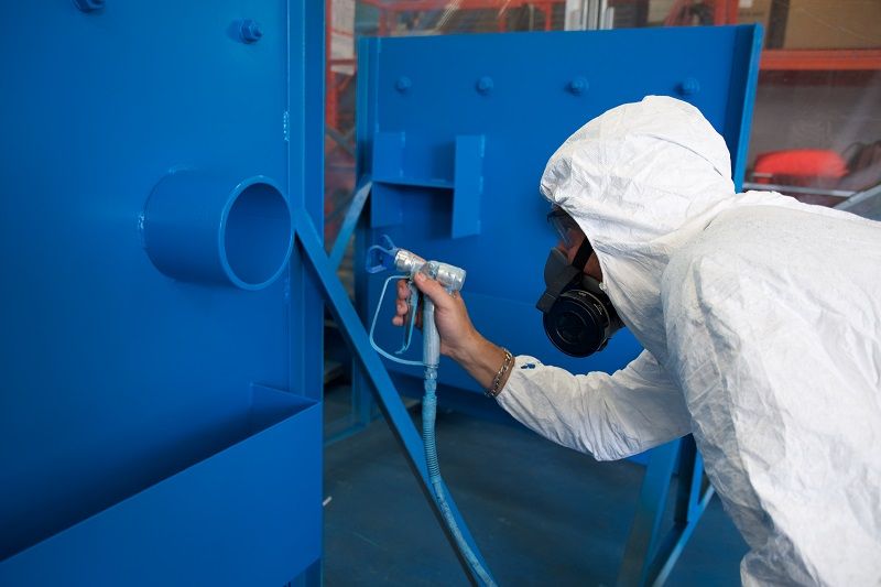 Painter using a spray paint machine for painting machinery.