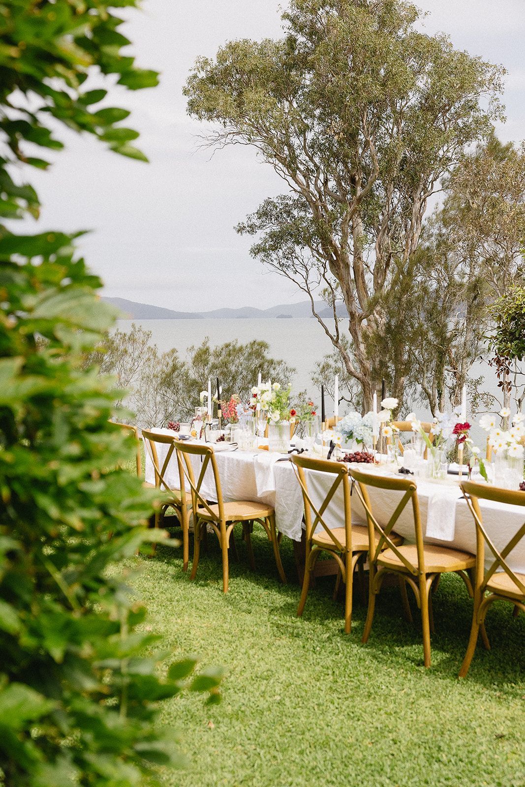 A long table and chairs set up for a wedding reception in the grass.