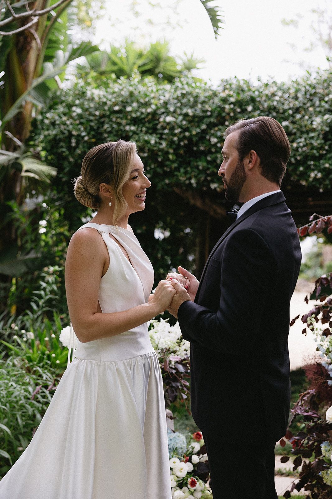 A bride and groom are holding hands and looking at each other.