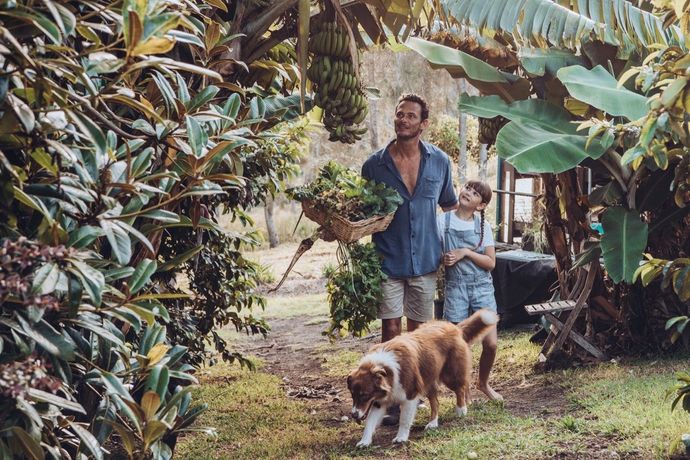 A man and a boy are walking a dog in a garden.