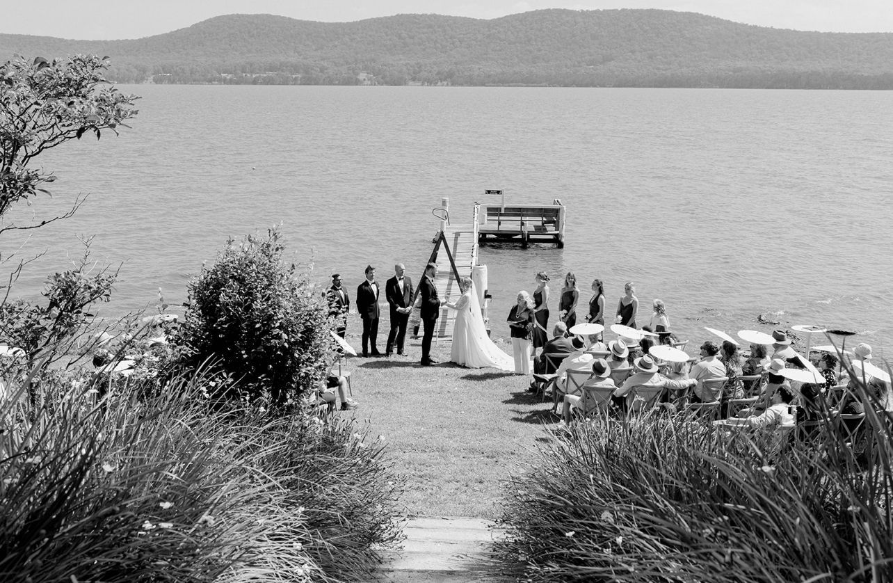 A black and white photo of a wedding ceremony on the shore of a lake.