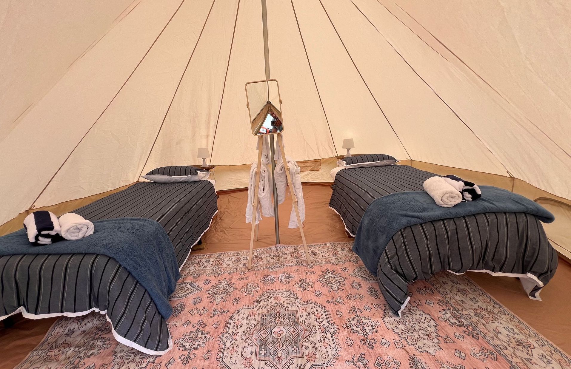 Two beds in a tent with a rug on the floor.