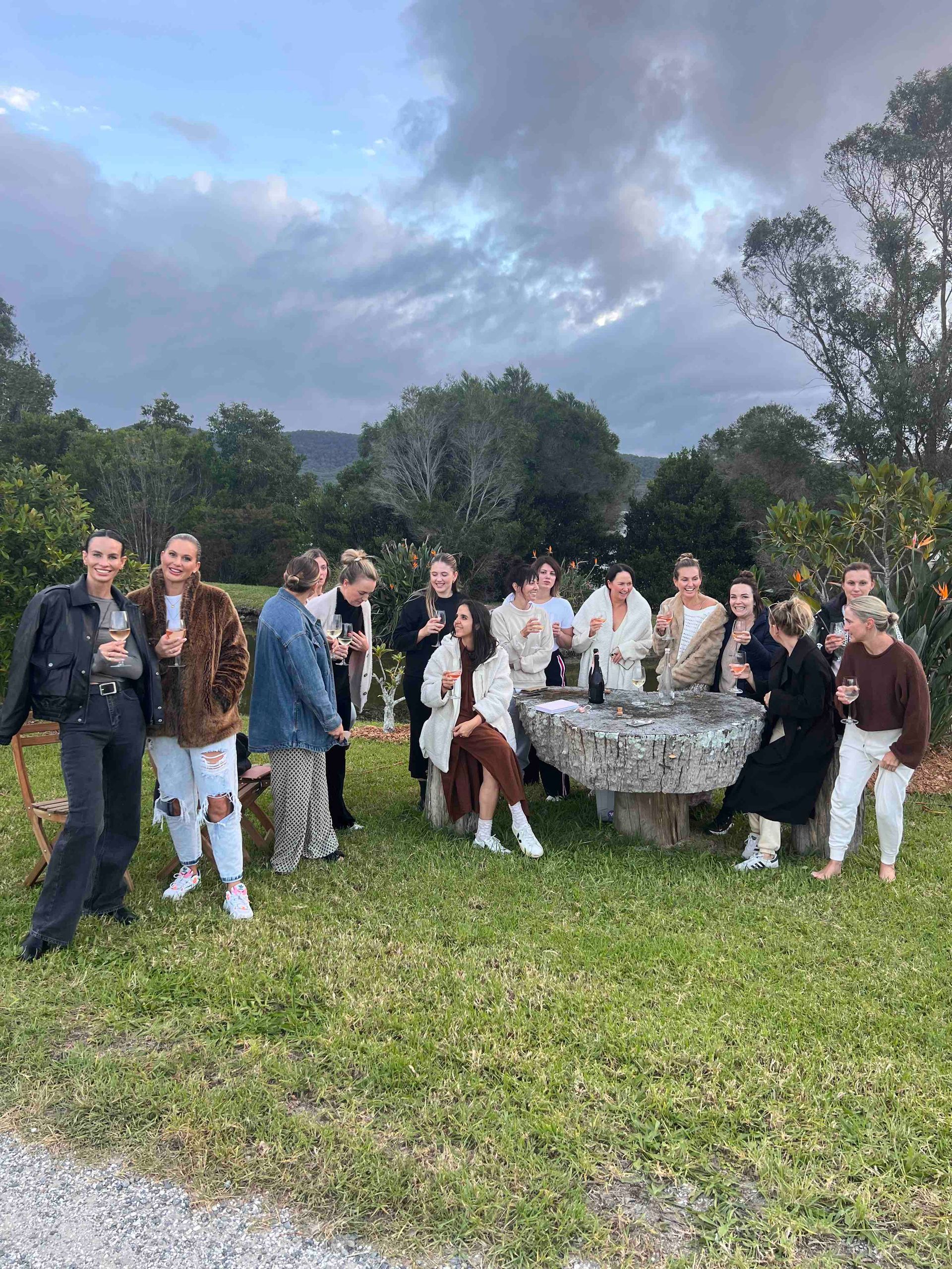 A group of people are standing in a field drinking wine.