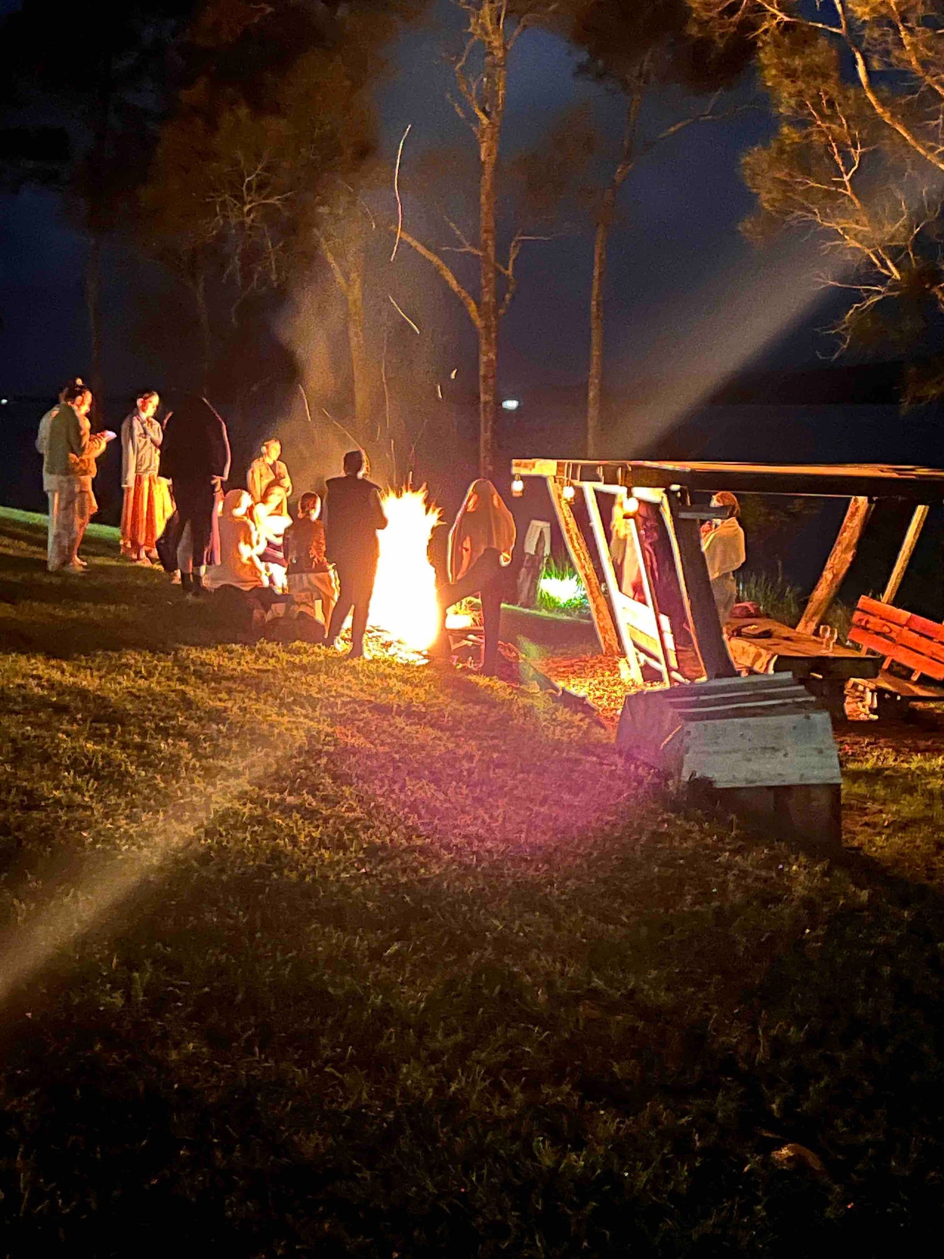 A group of people standing around a fire at night
