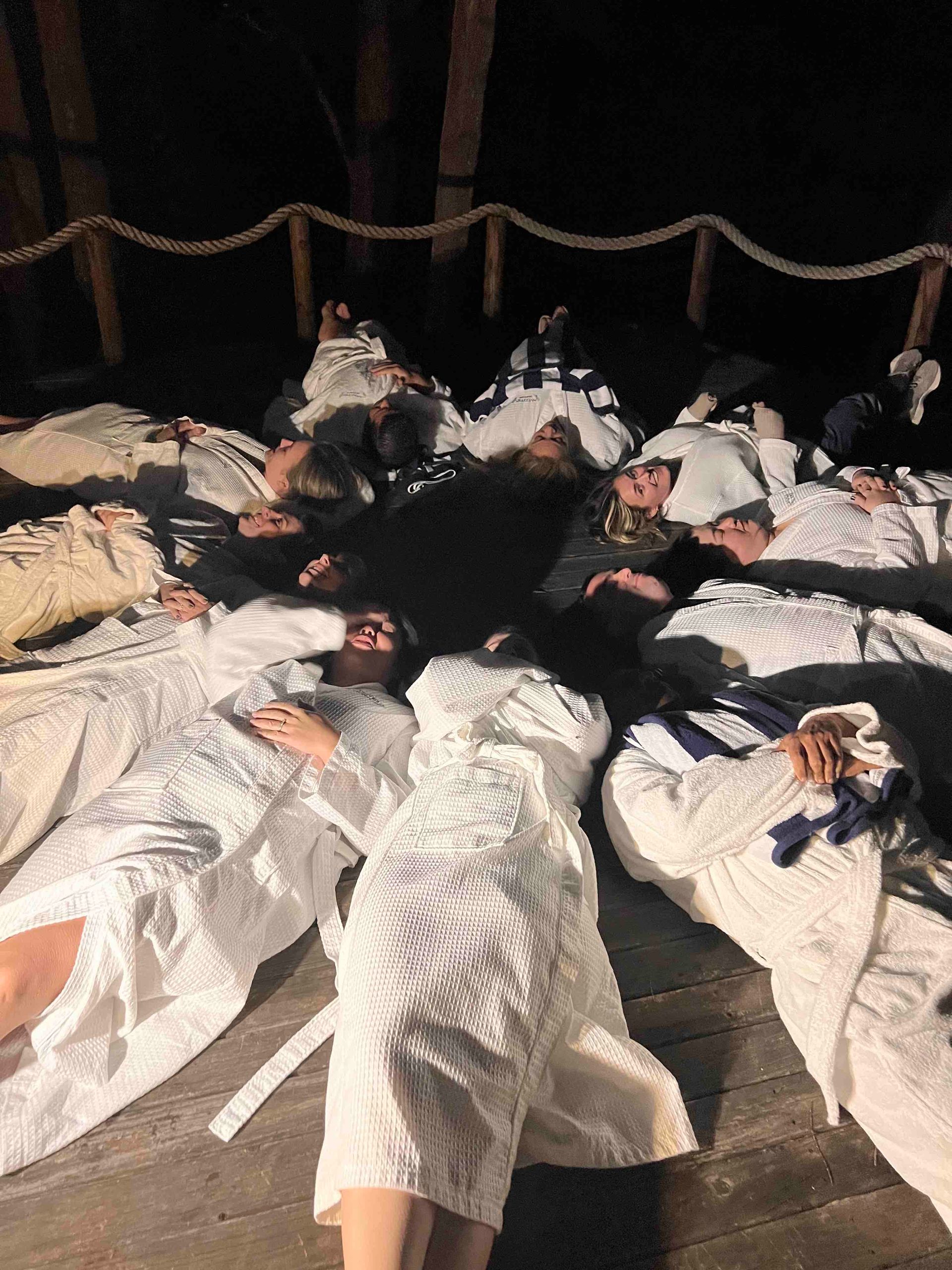A group of people are laying on the ground in a circle.