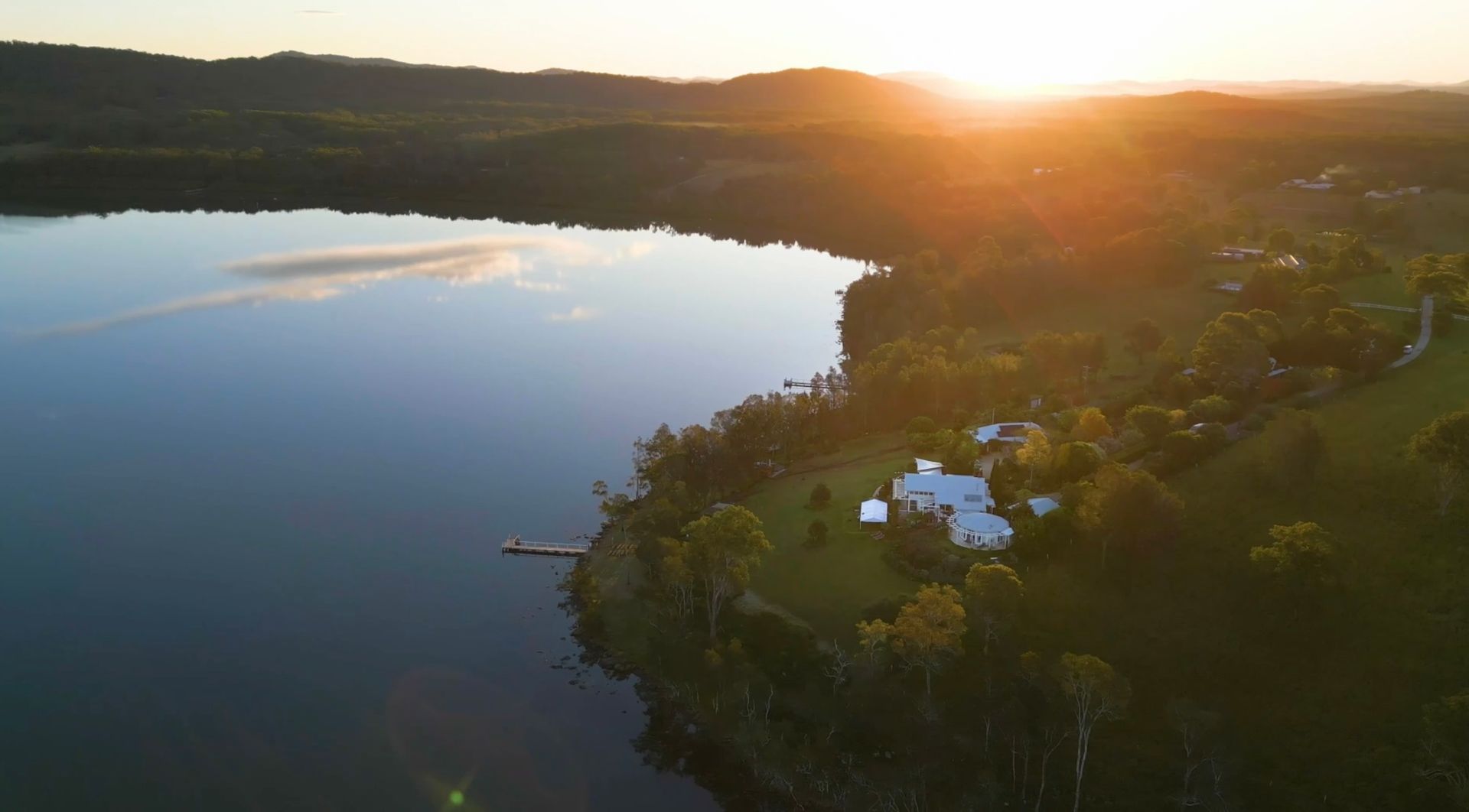 An aerial view of a lake surrounded by trees at sunset.