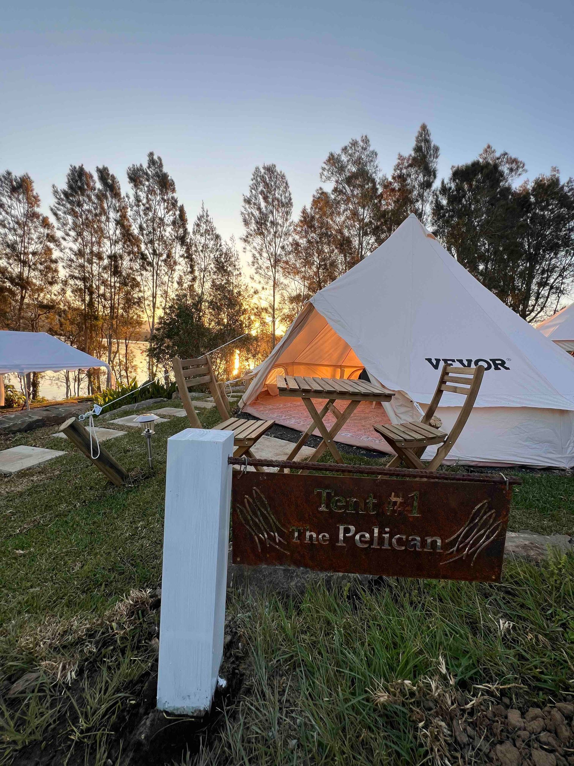 A tent is sitting in the middle of a field next to a sign.