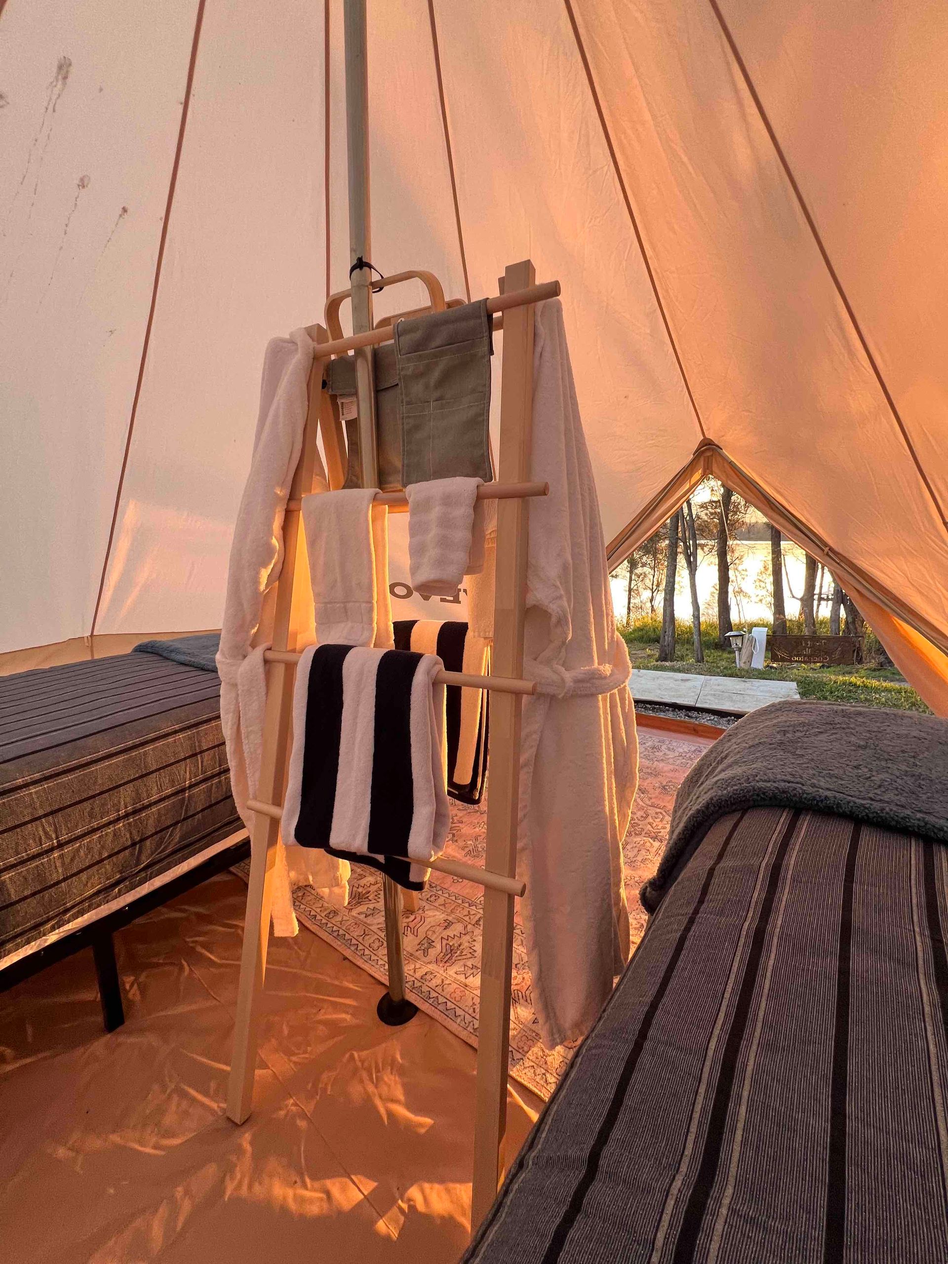 A ladder with towels hanging from it in a tent.