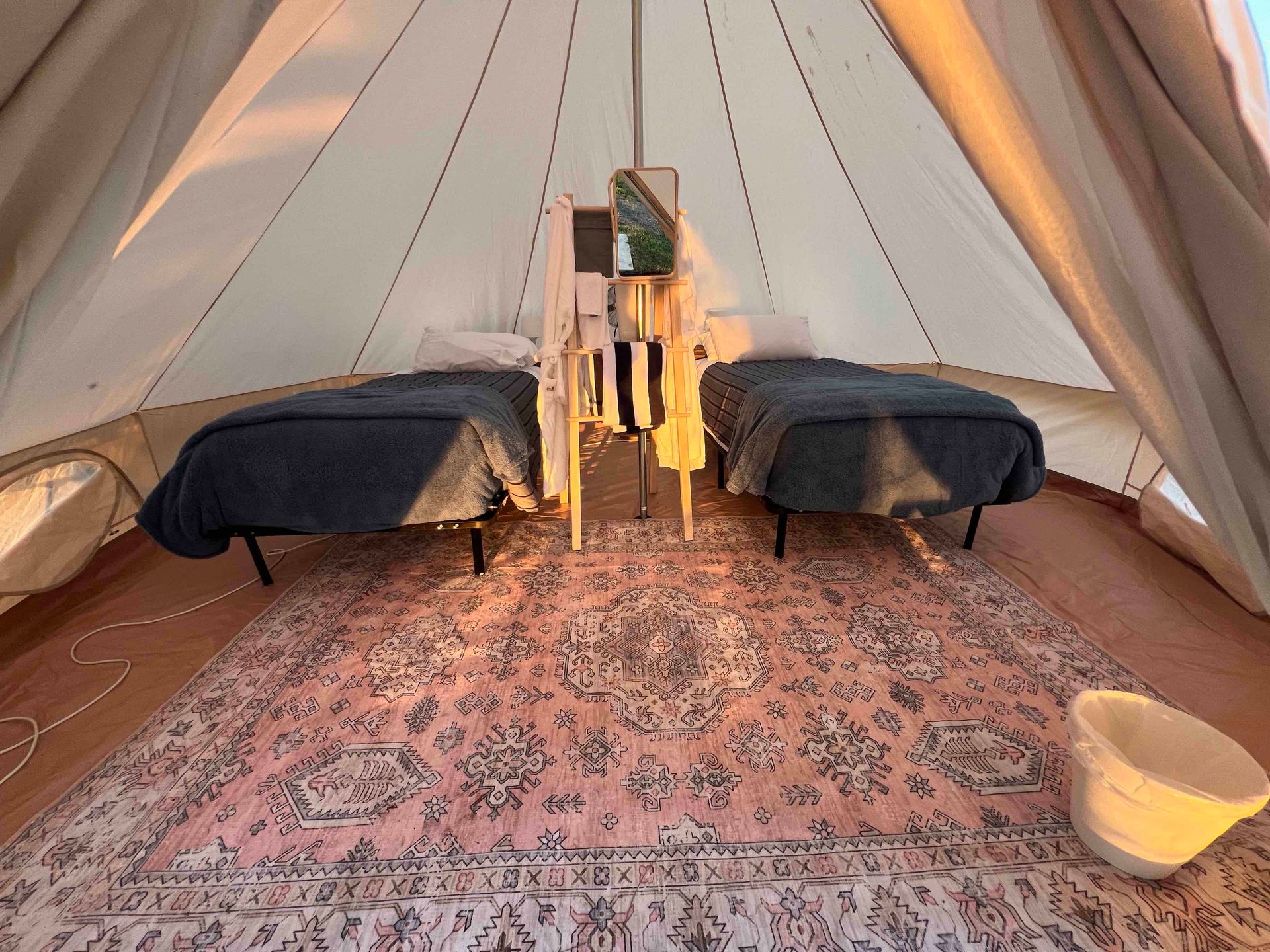 A tent with two beds and a rug inside of it.