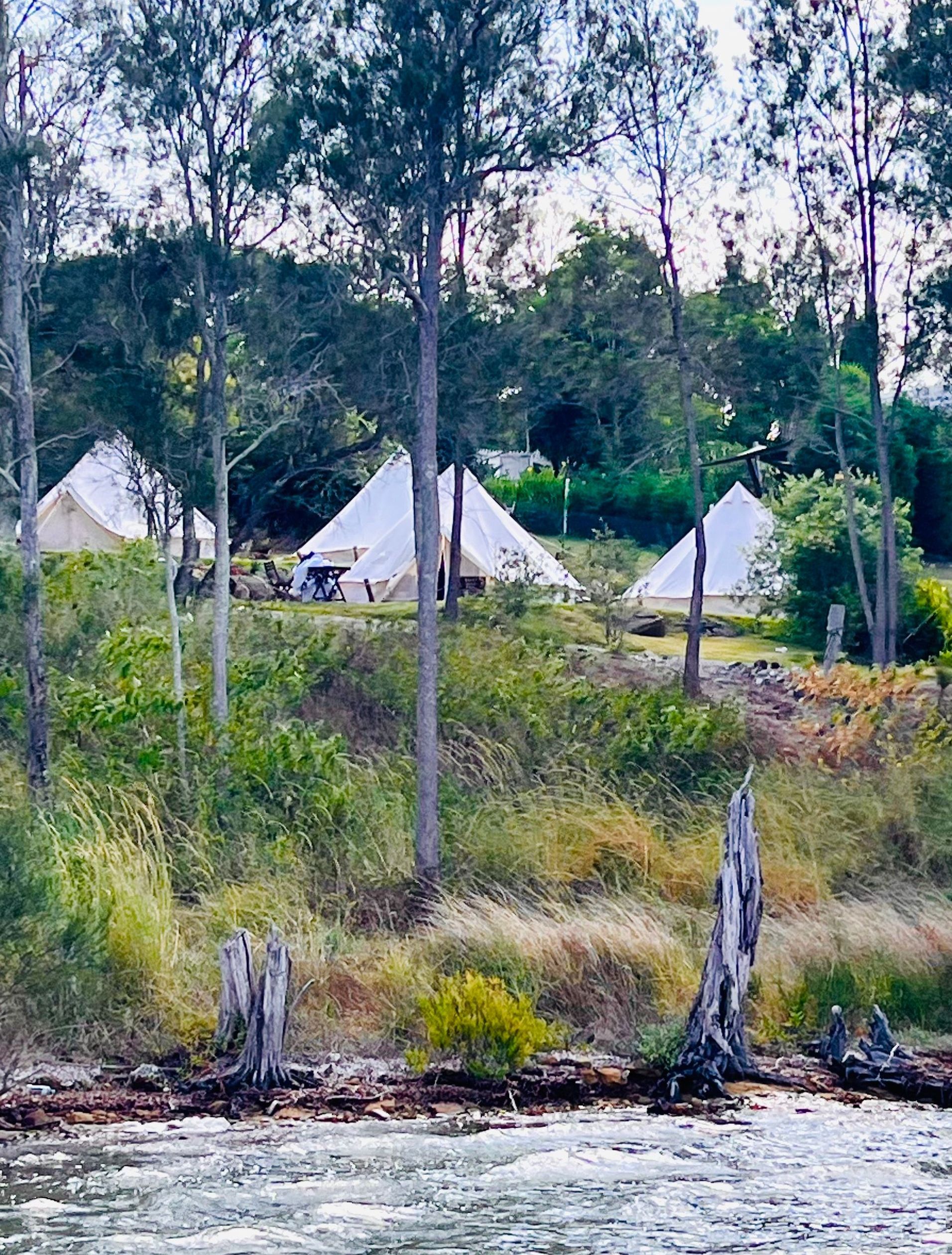 A group of tents are sitting on top of a hill next to a river.