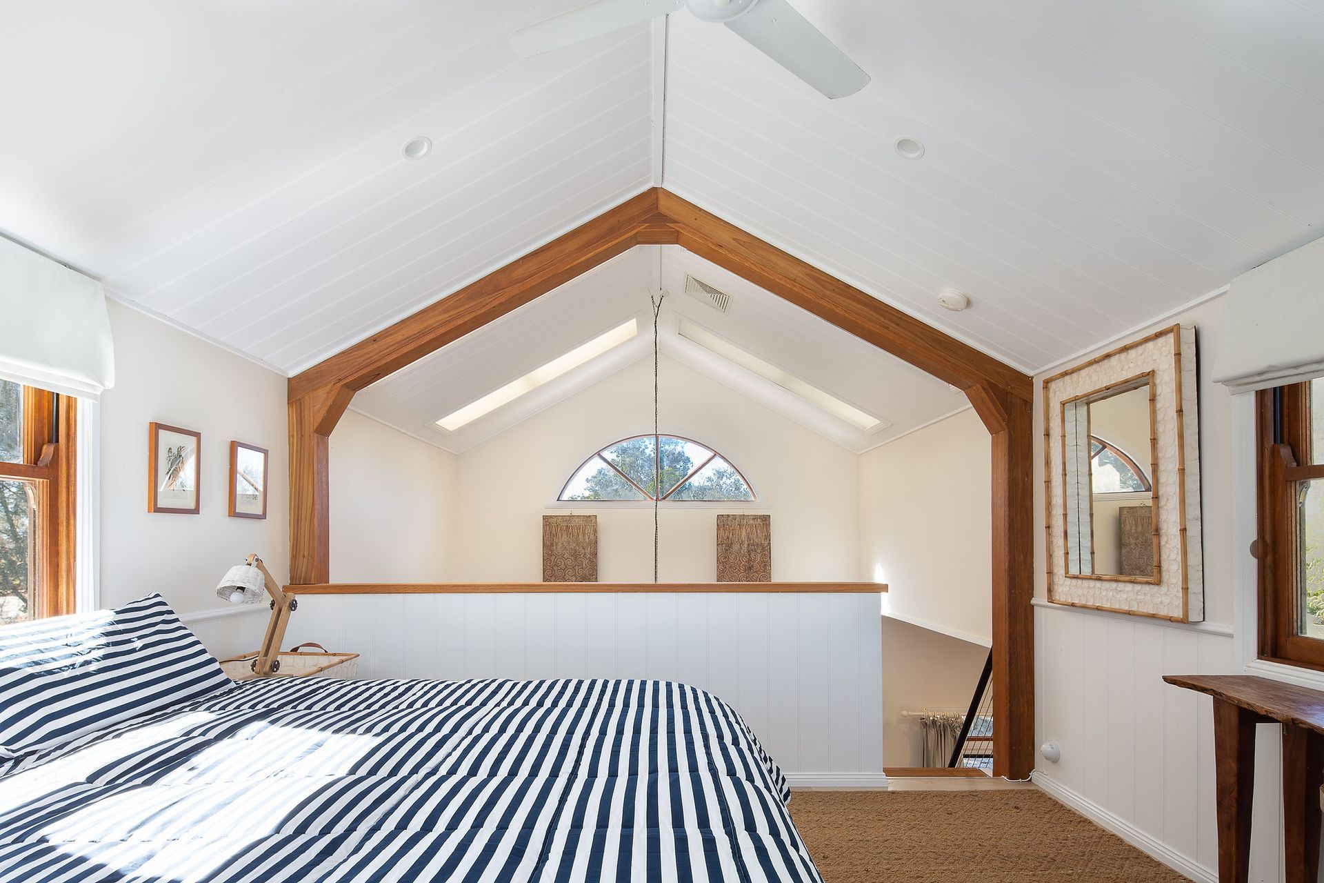 A bedroom with a striped bed and a ceiling fan.