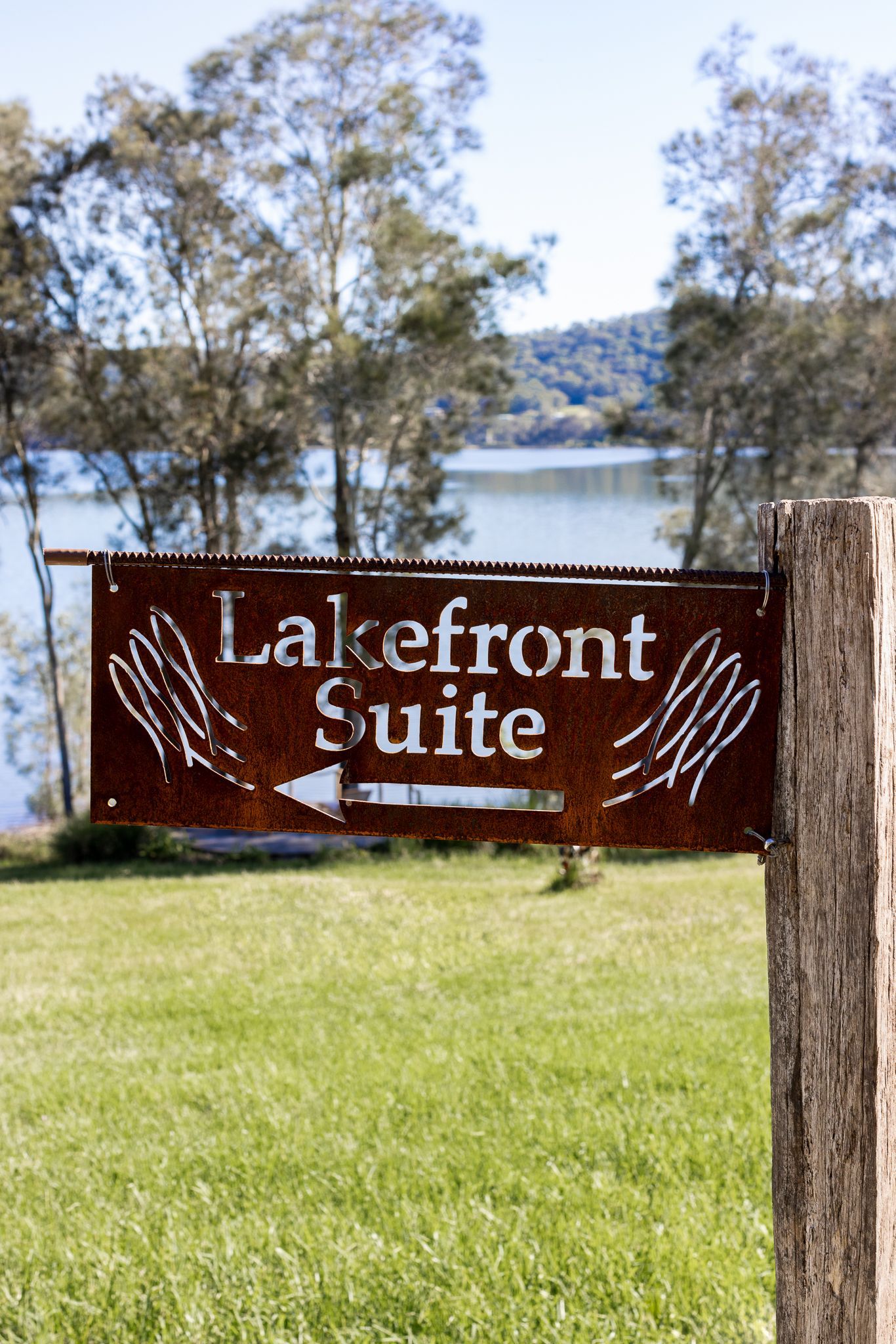 A sign that says lakefront suite is hanging on a wooden post.