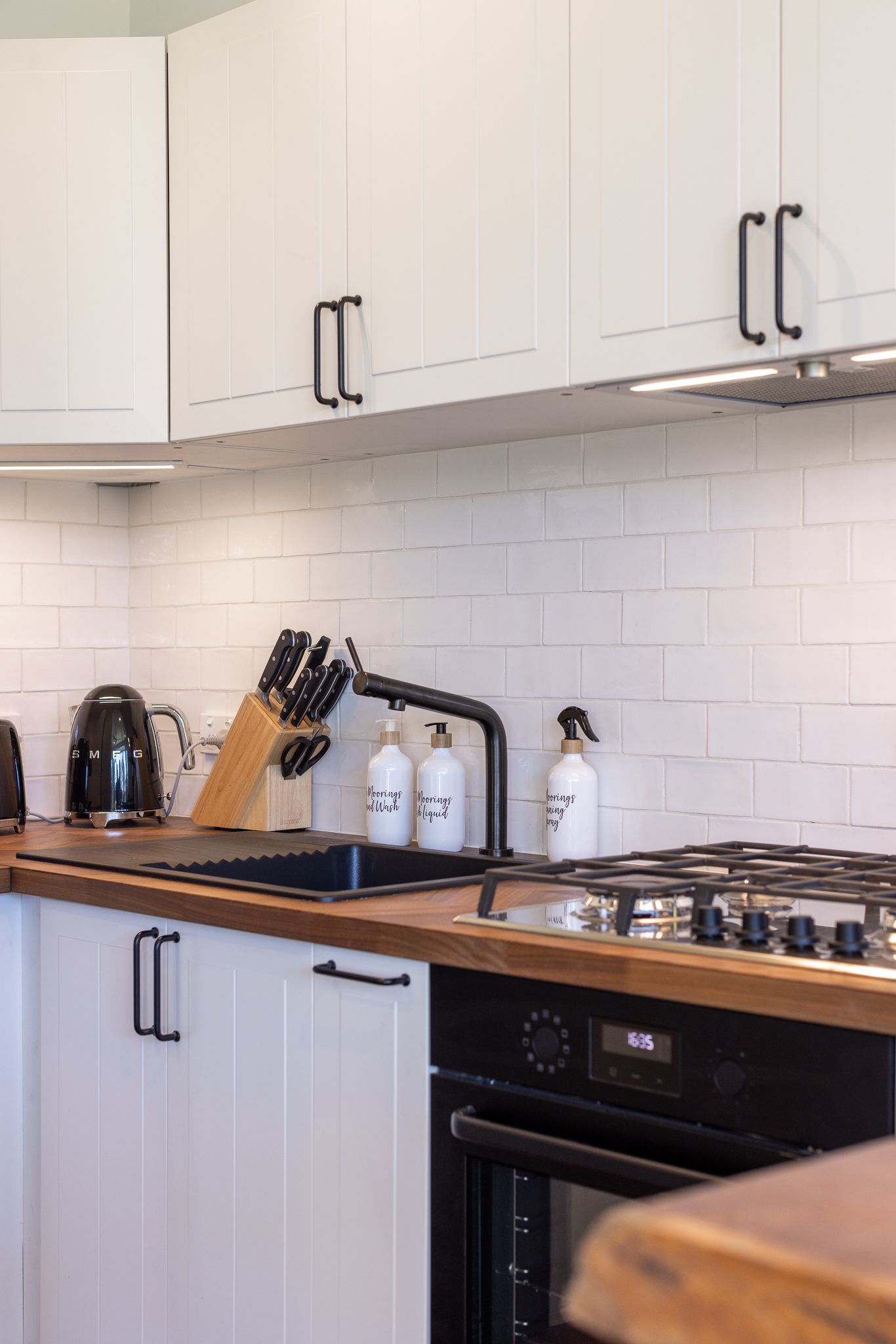 A kitchen with white cabinets and a wooden counter top