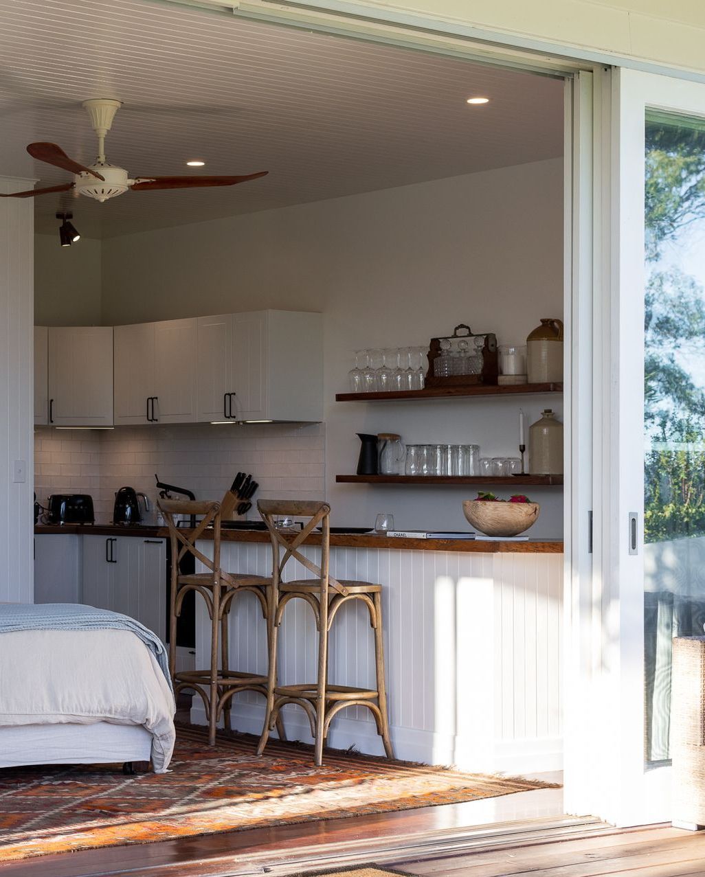 A bedroom with a sliding glass door leading to a kitchen