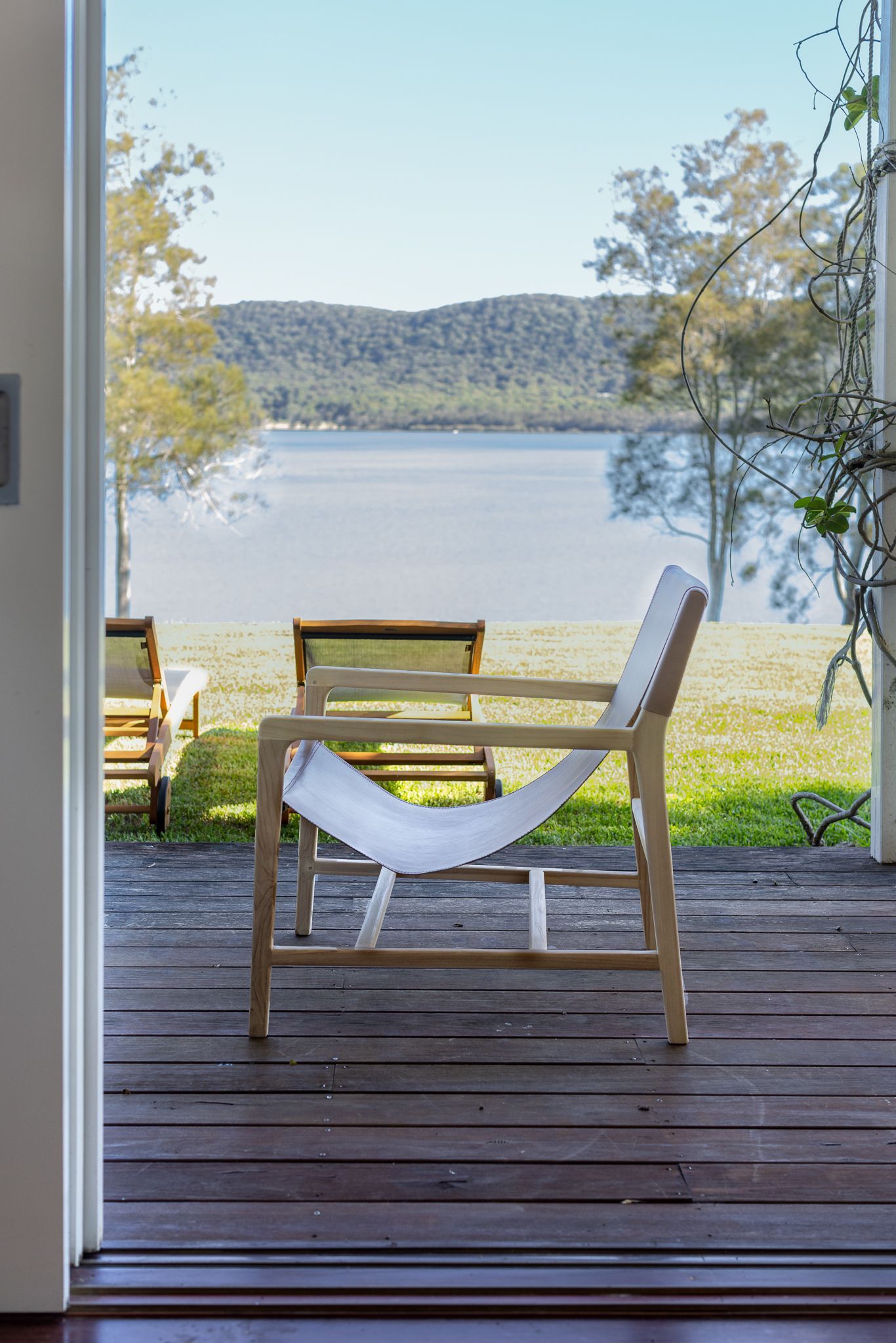 A chair is sitting on a wooden deck overlooking a lake.
