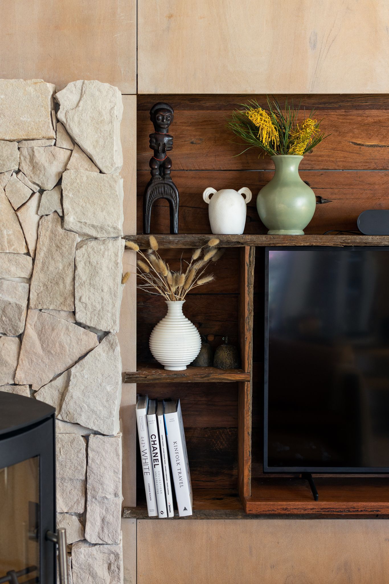 A living room with a fireplace and a television on a shelf.