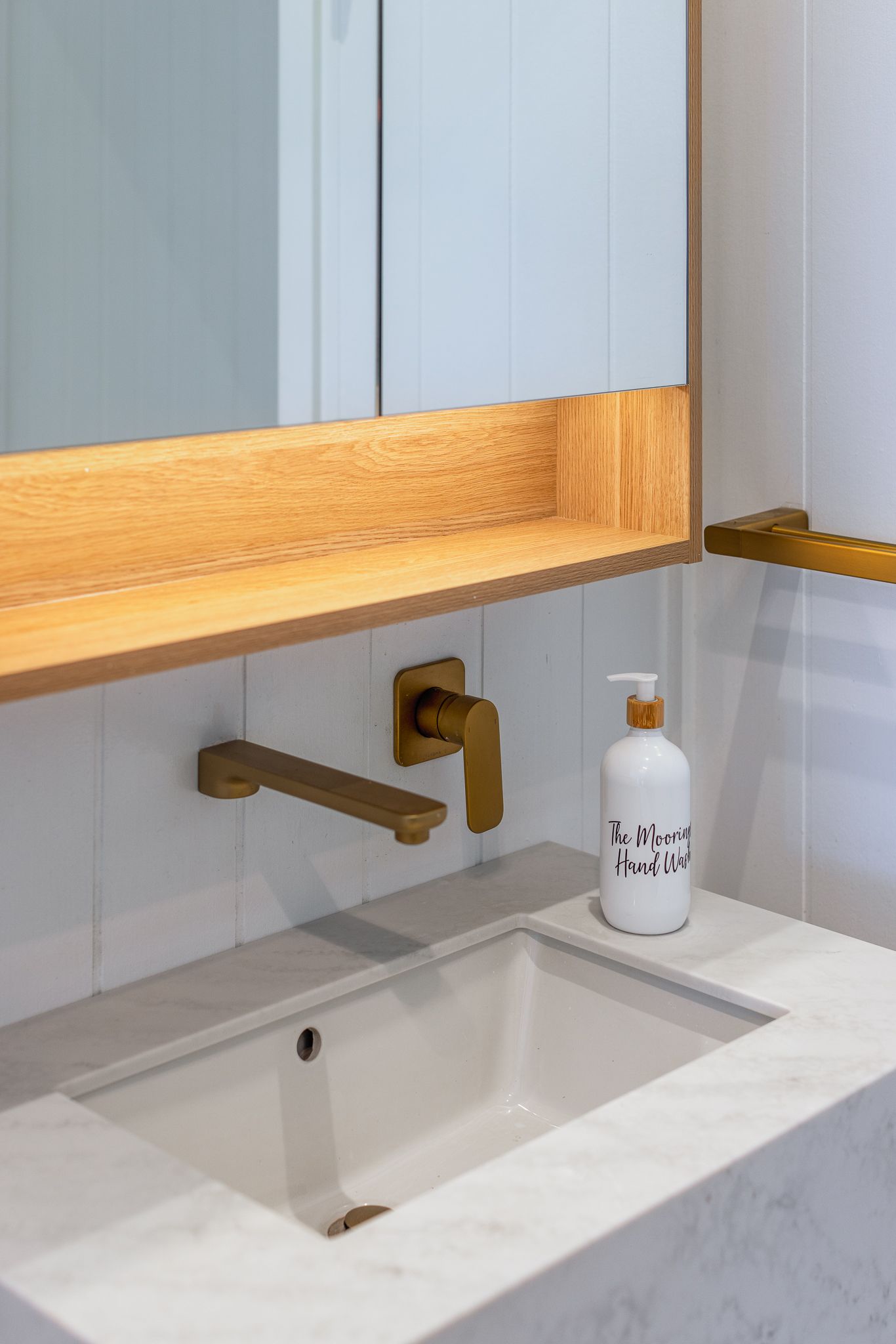 A bathroom sink with a soap dispenser and a mirror.