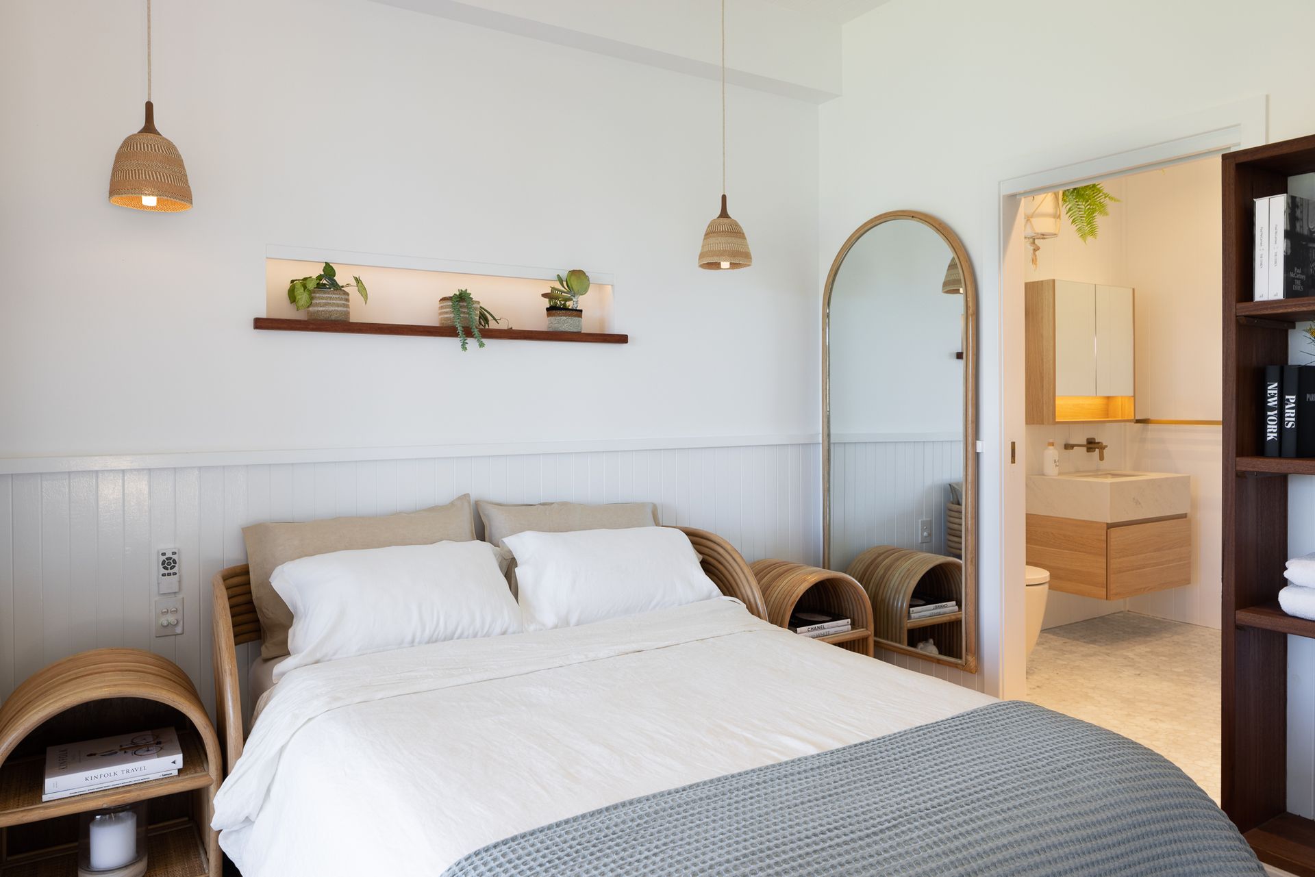 A bedroom with a bed , nightstands , a mirror and a bathroom.