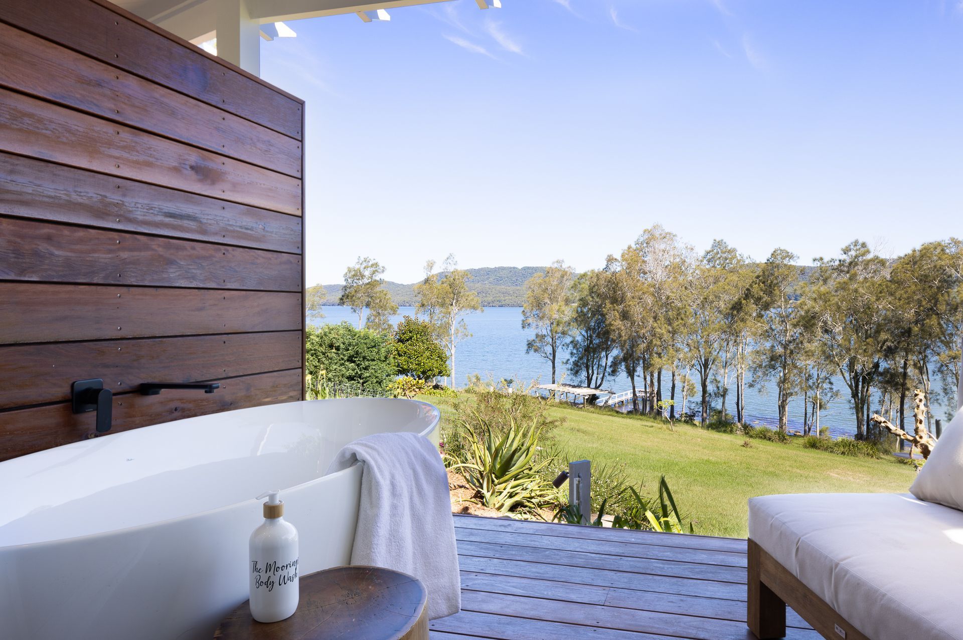 A bathtub on a balcony overlooking a body of water.