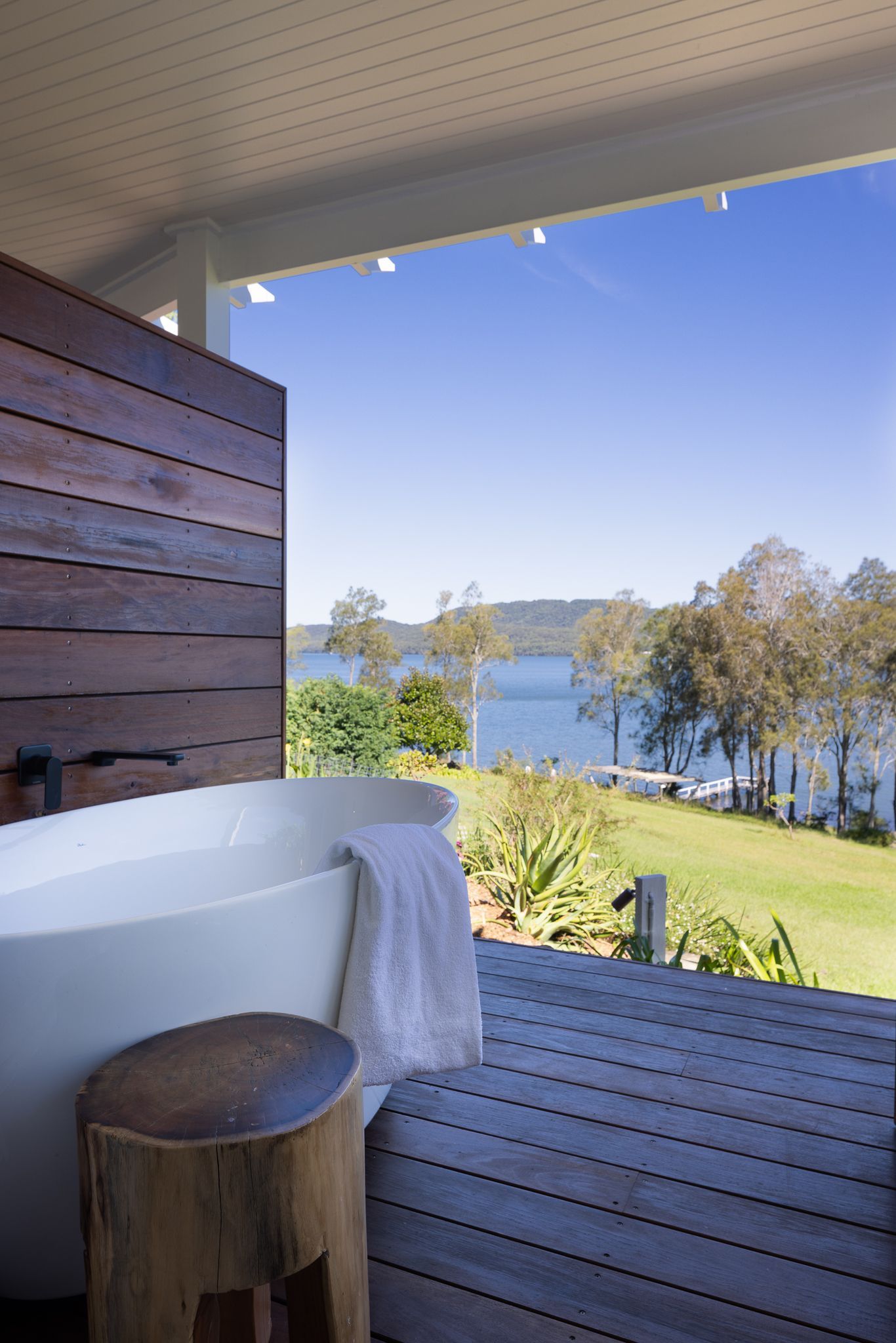 There is a bathtub on the deck with a view of the water.
