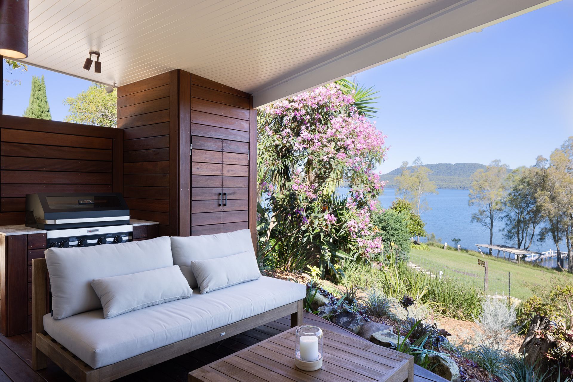 A patio with a couch and a table with a view of a lake.