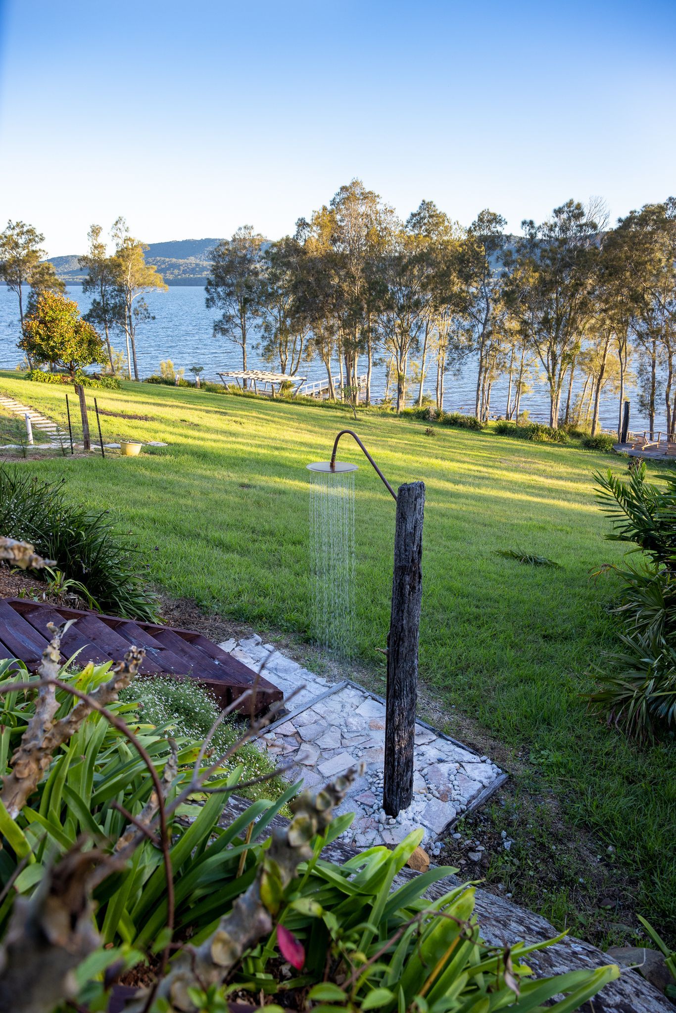 A garden with a shower and a view of the ocean.
