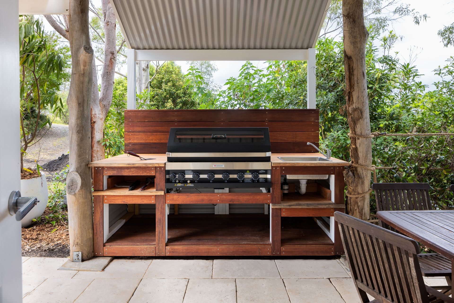 An outdoor kitchen with a grill and a table and chairs