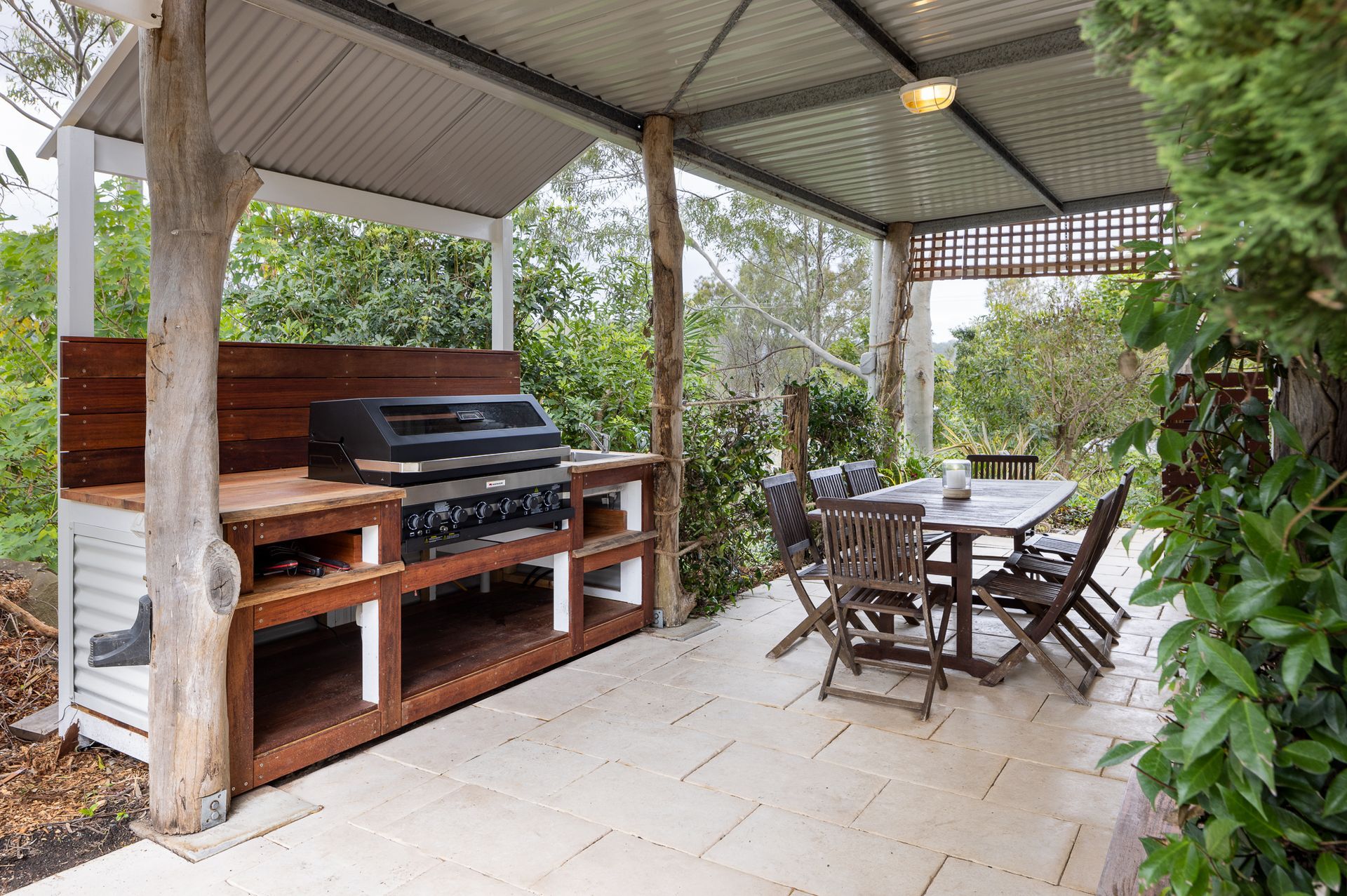 A covered patio with a table and chairs and a grill.