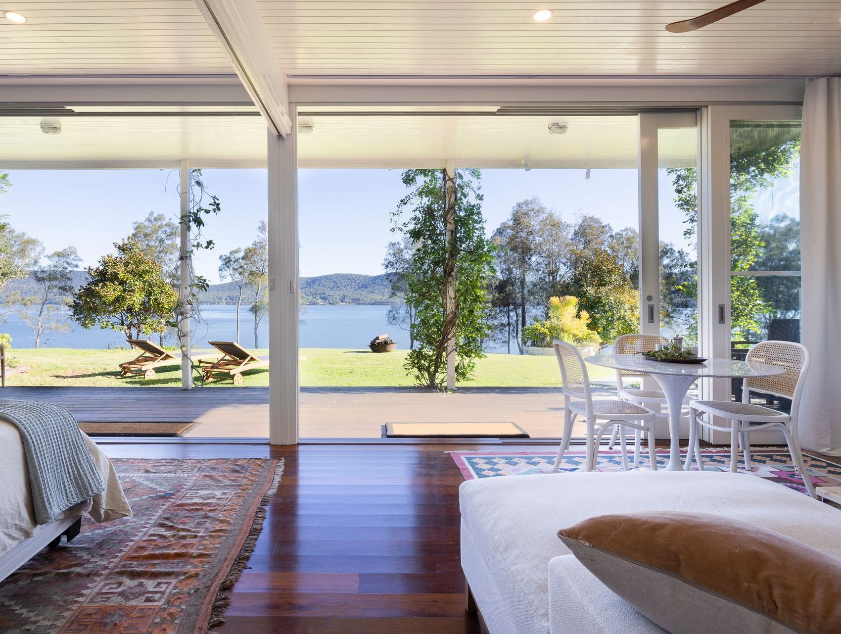 A bedroom with a view of a lake and a table and chairs