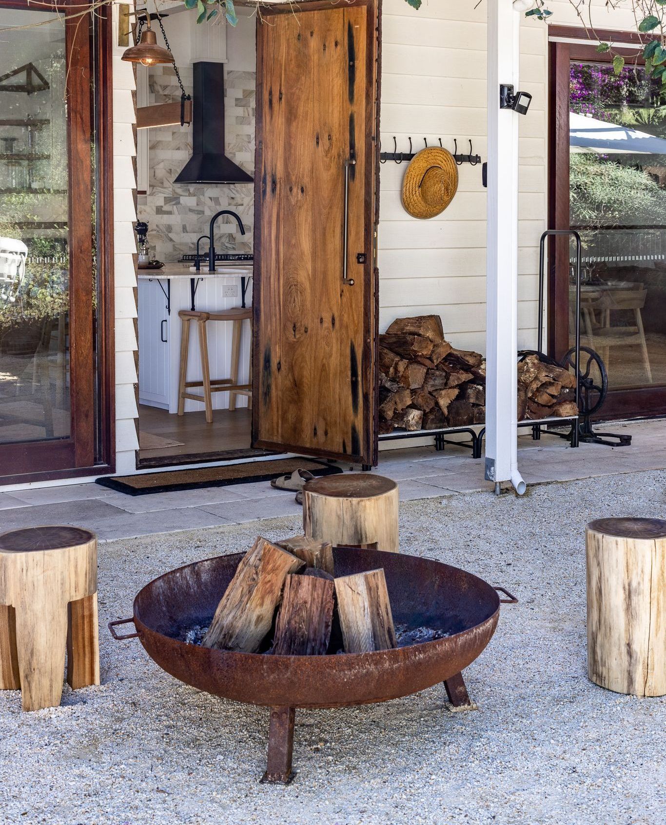 A fire pit with logs in it in front of a house