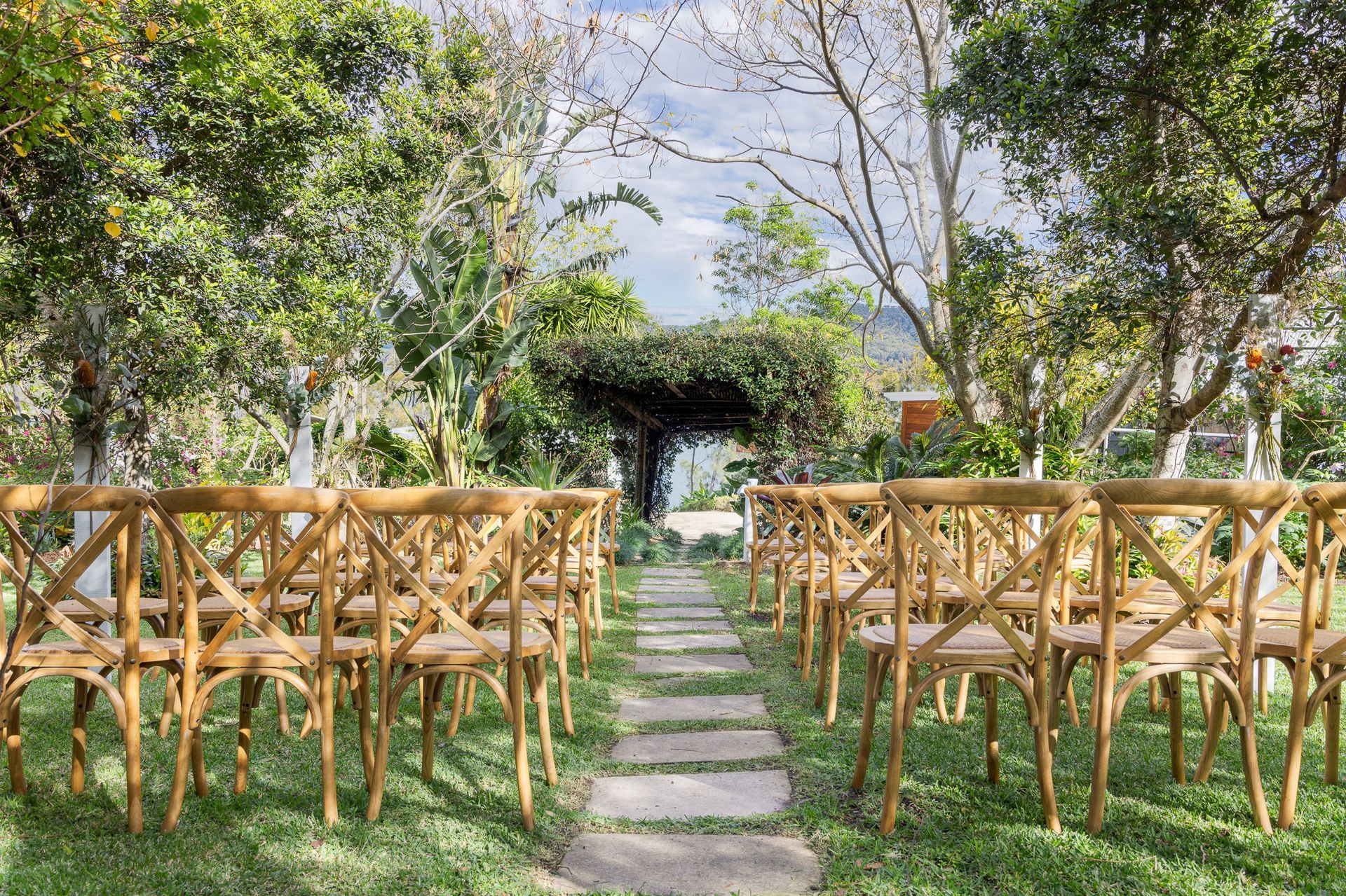 A row of wooden chairs are lined up in a lush green field.