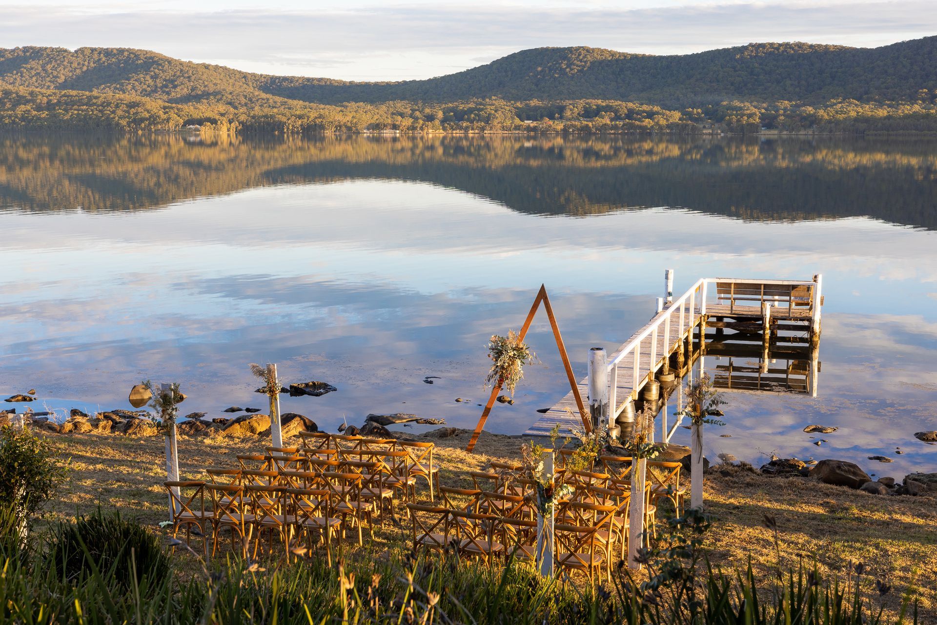 There is a dock in the middle of a lake with mountains in the background.