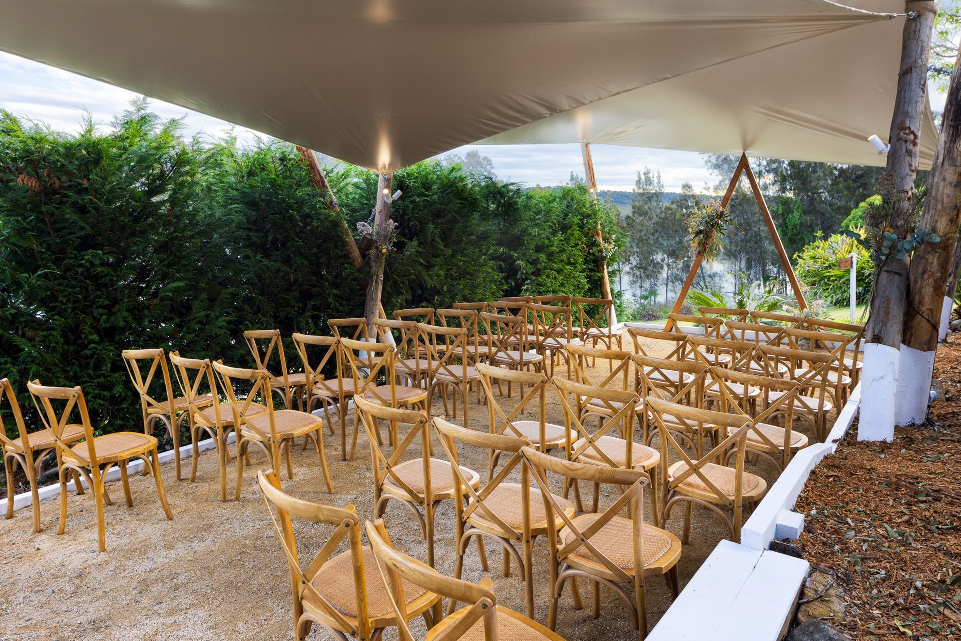 A row of wooden chairs under a tent.
