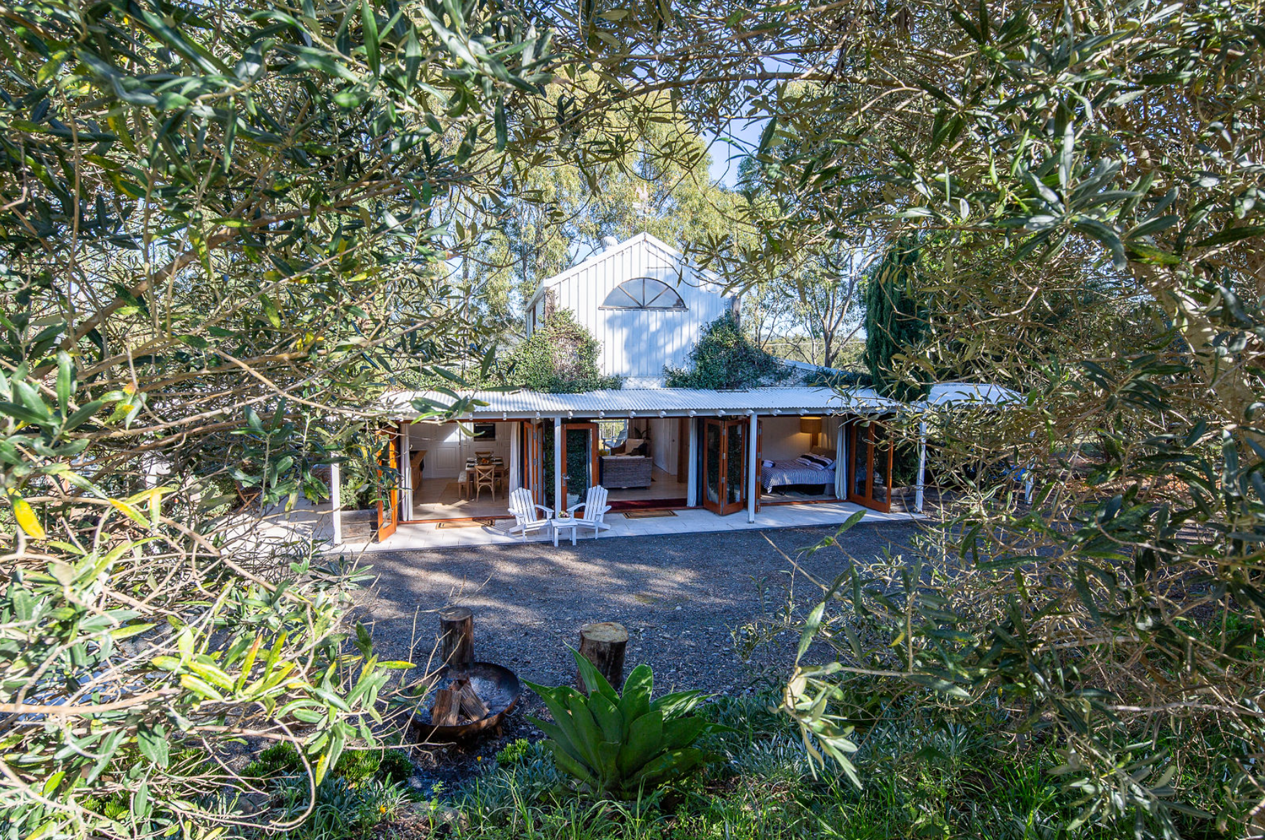 A white house with a porch is surrounded by trees.