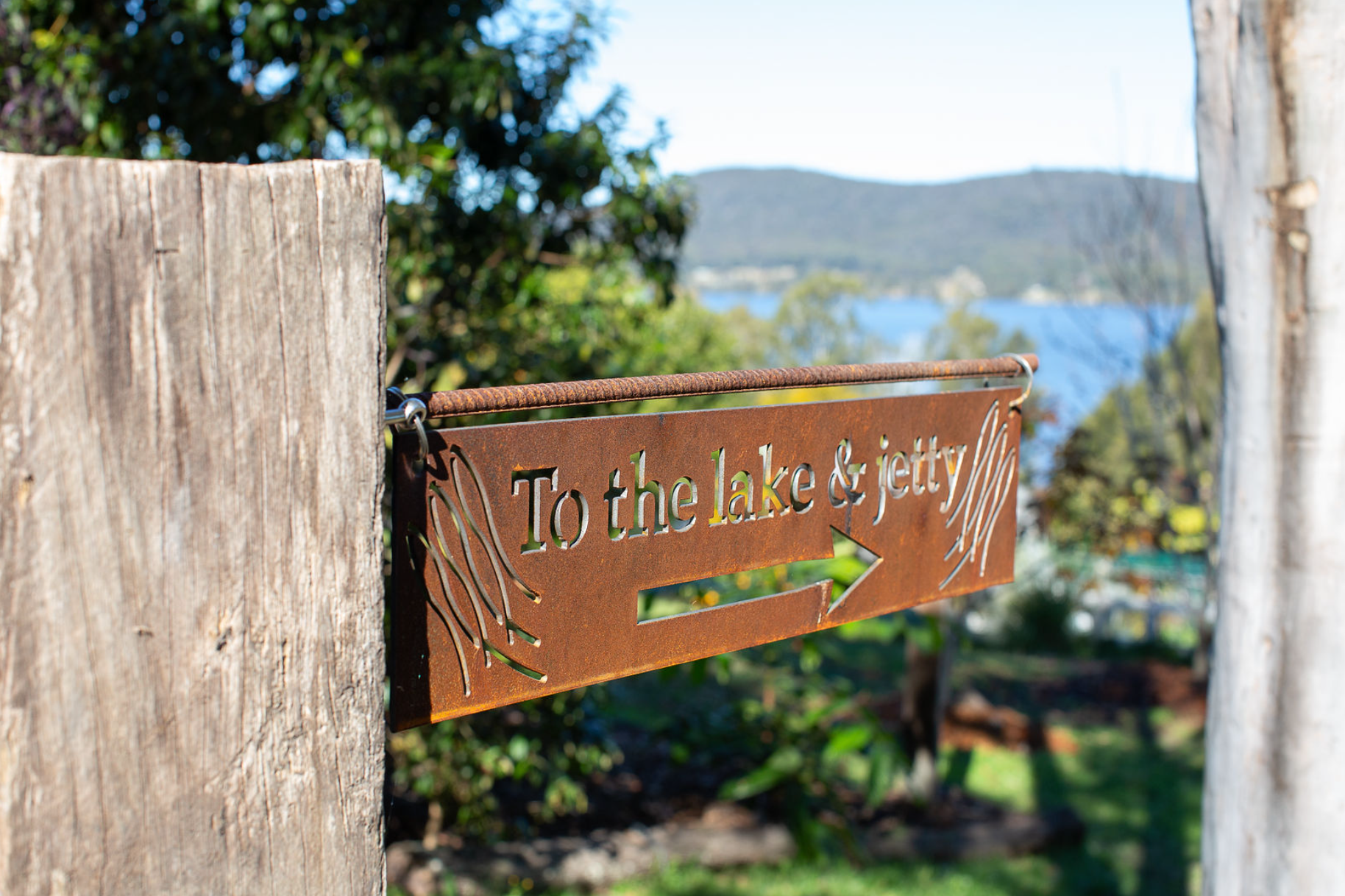 A rusty sign on a wooden post says to the lake and jetty