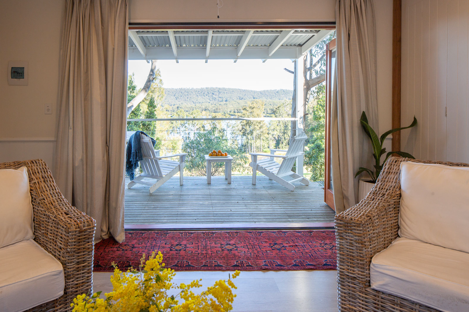 A living room with two chairs and a table with a view of a deck.