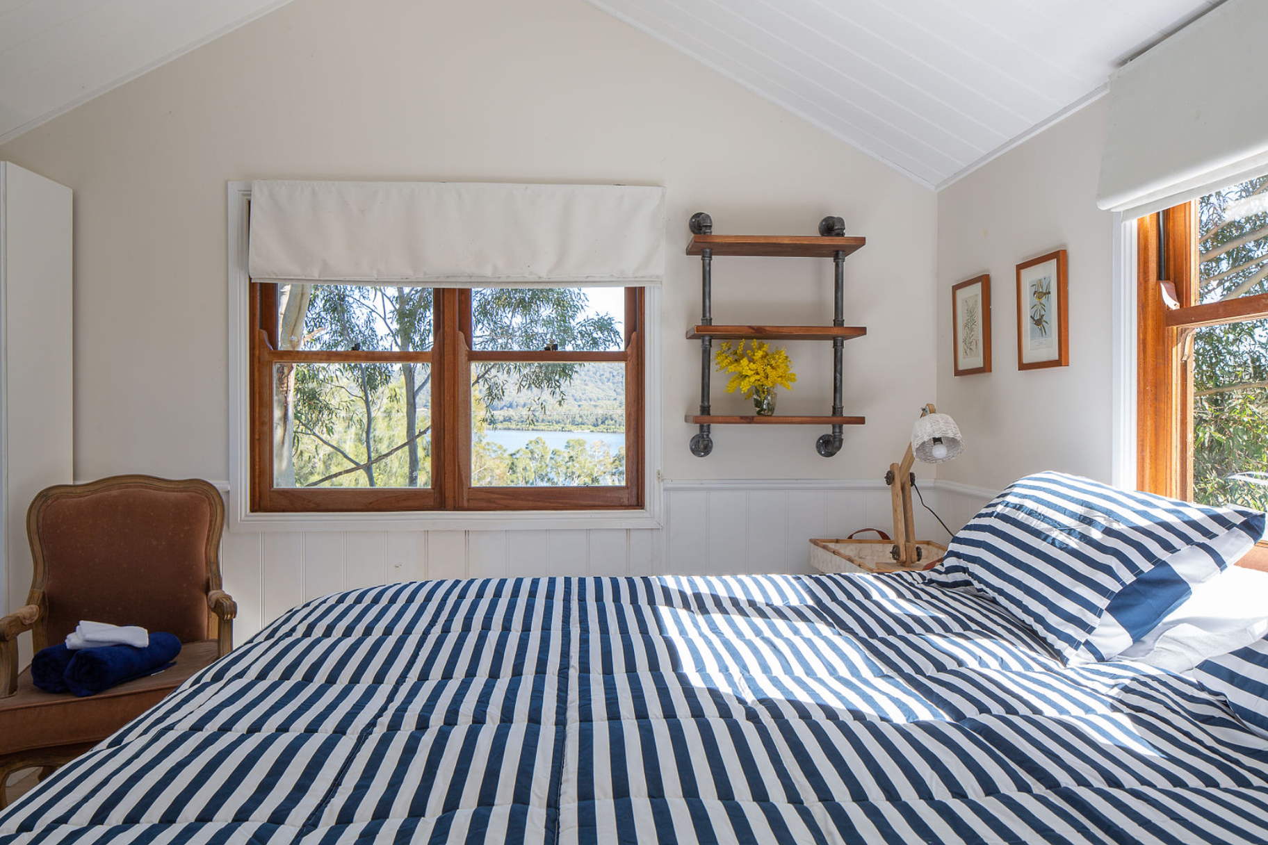 A bedroom with a striped bed and a chair
