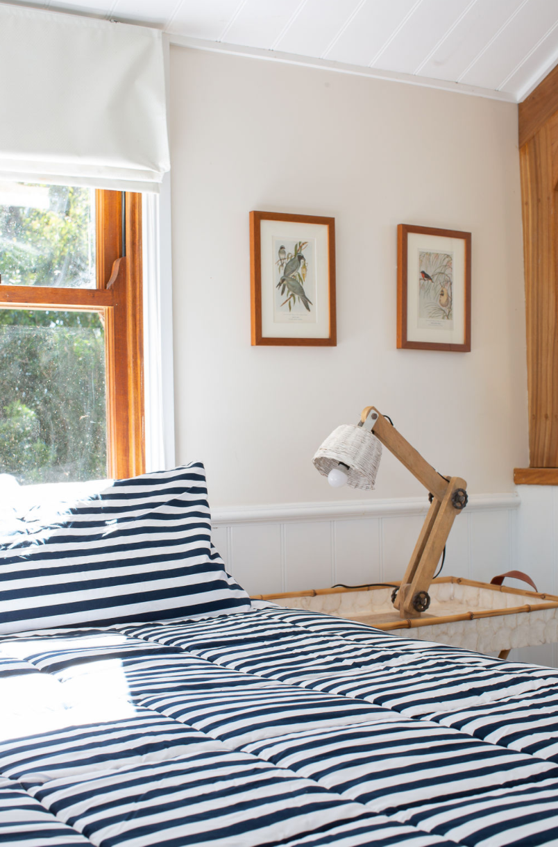 A bedroom with a striped bedspread and a lamp